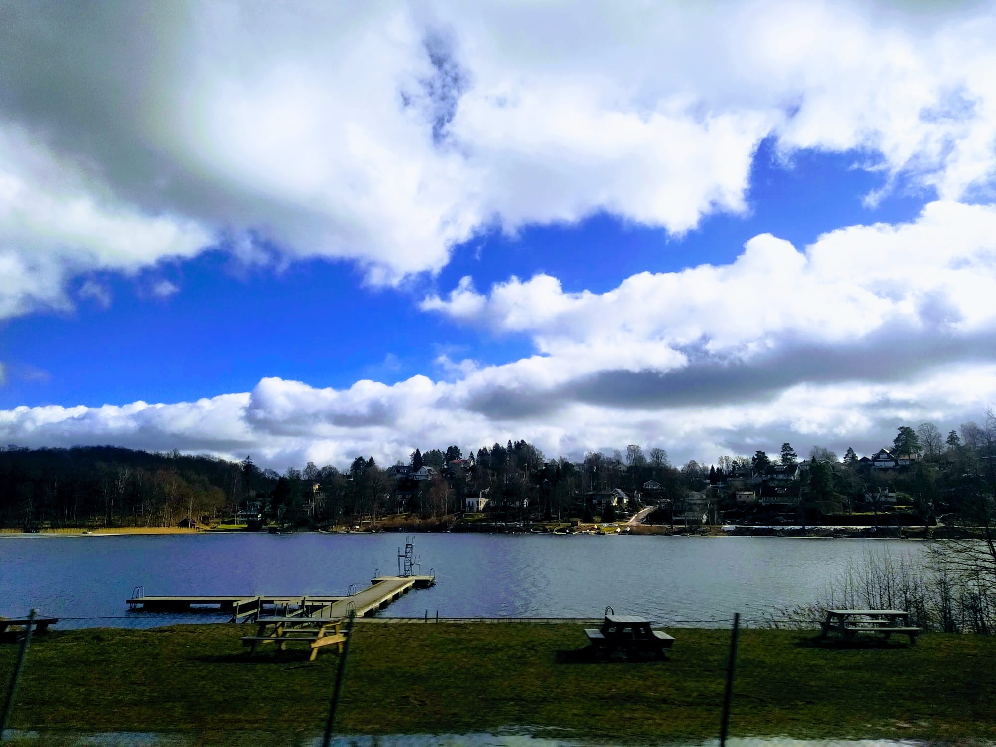 Park tables and a jetty next to a lake.