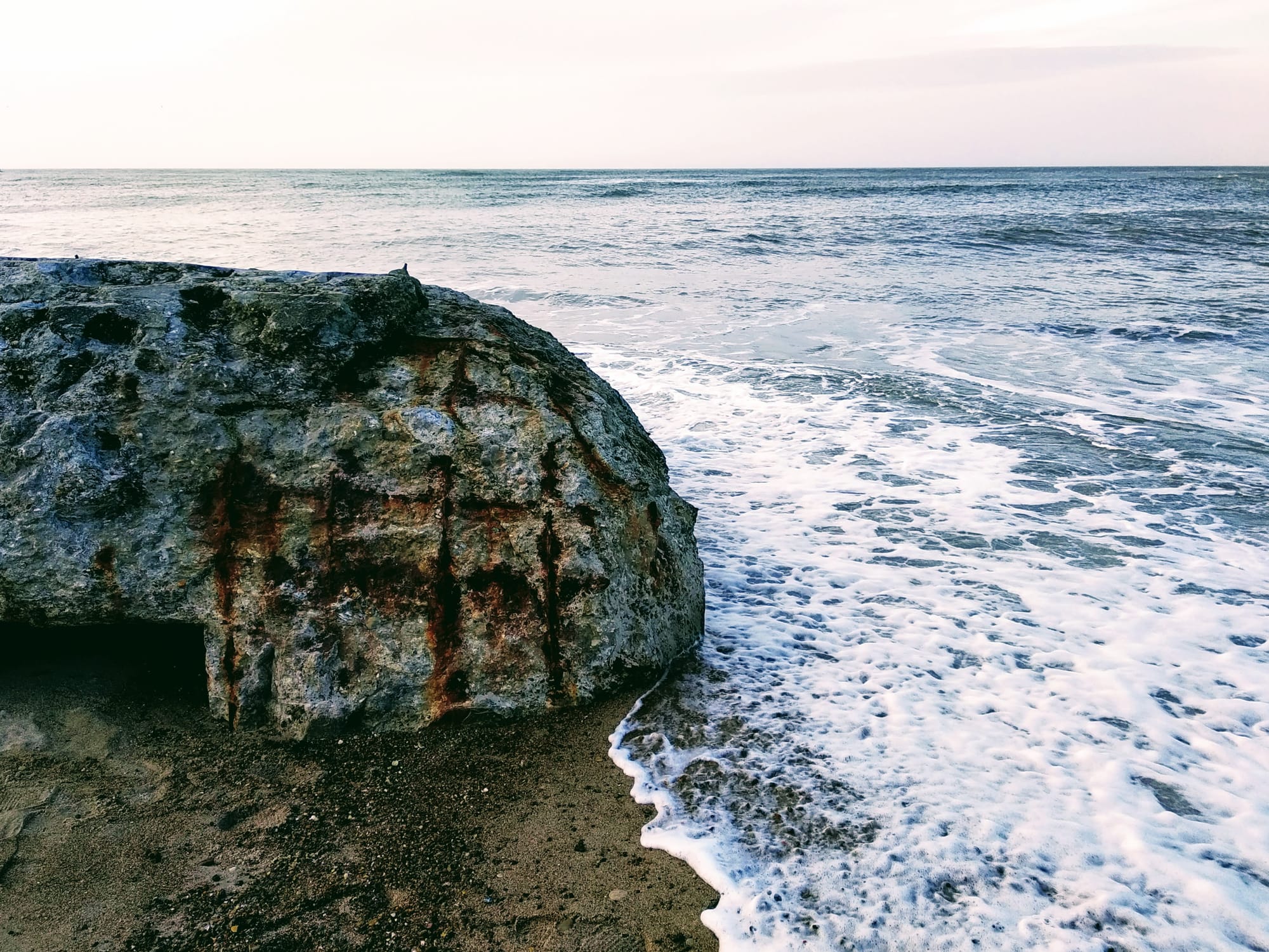 The north sea laps against the remains of a WWII bunker partly submerged in the beach at Klitmøller.