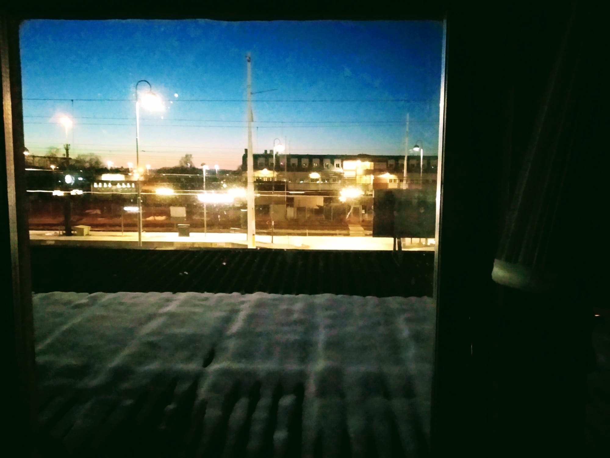 The platforms of Norrköping Centralstation seen across a snowy roof from a hostel room window.