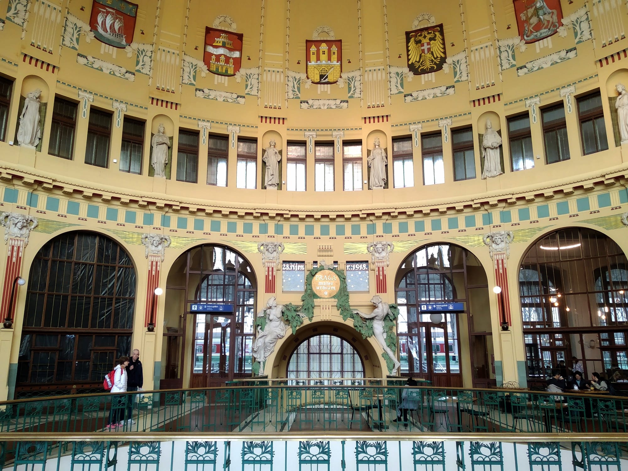 Two people look over the steel railings of the dome in Prague's central station.