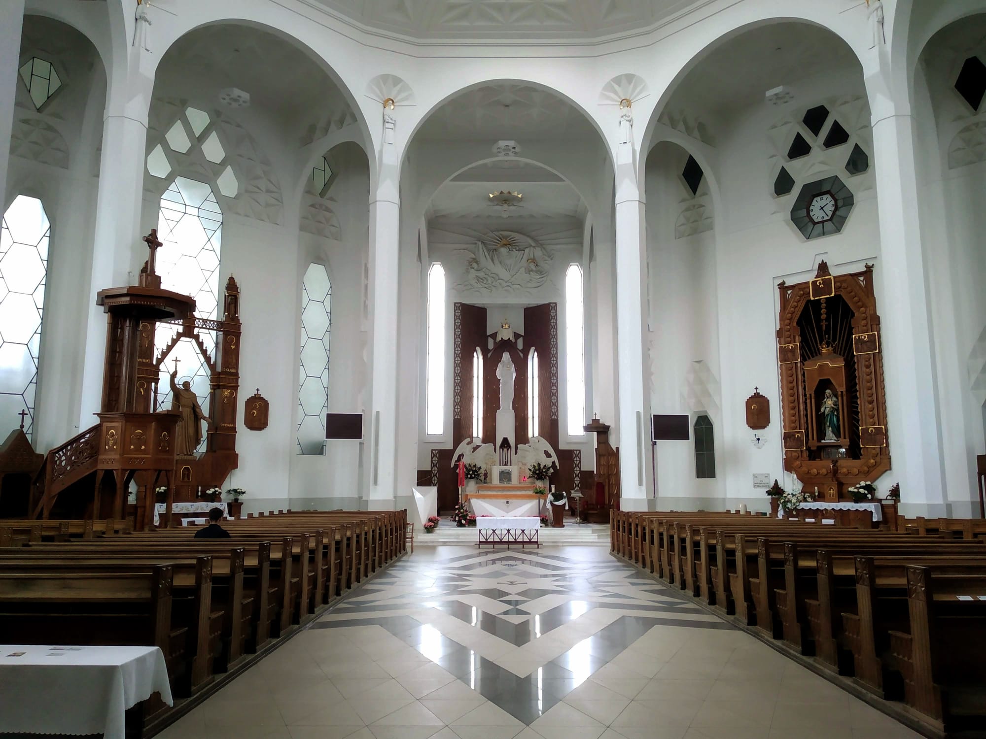 The white interior of the Basilica of Saint Roch, looking towards the chancel and altar.