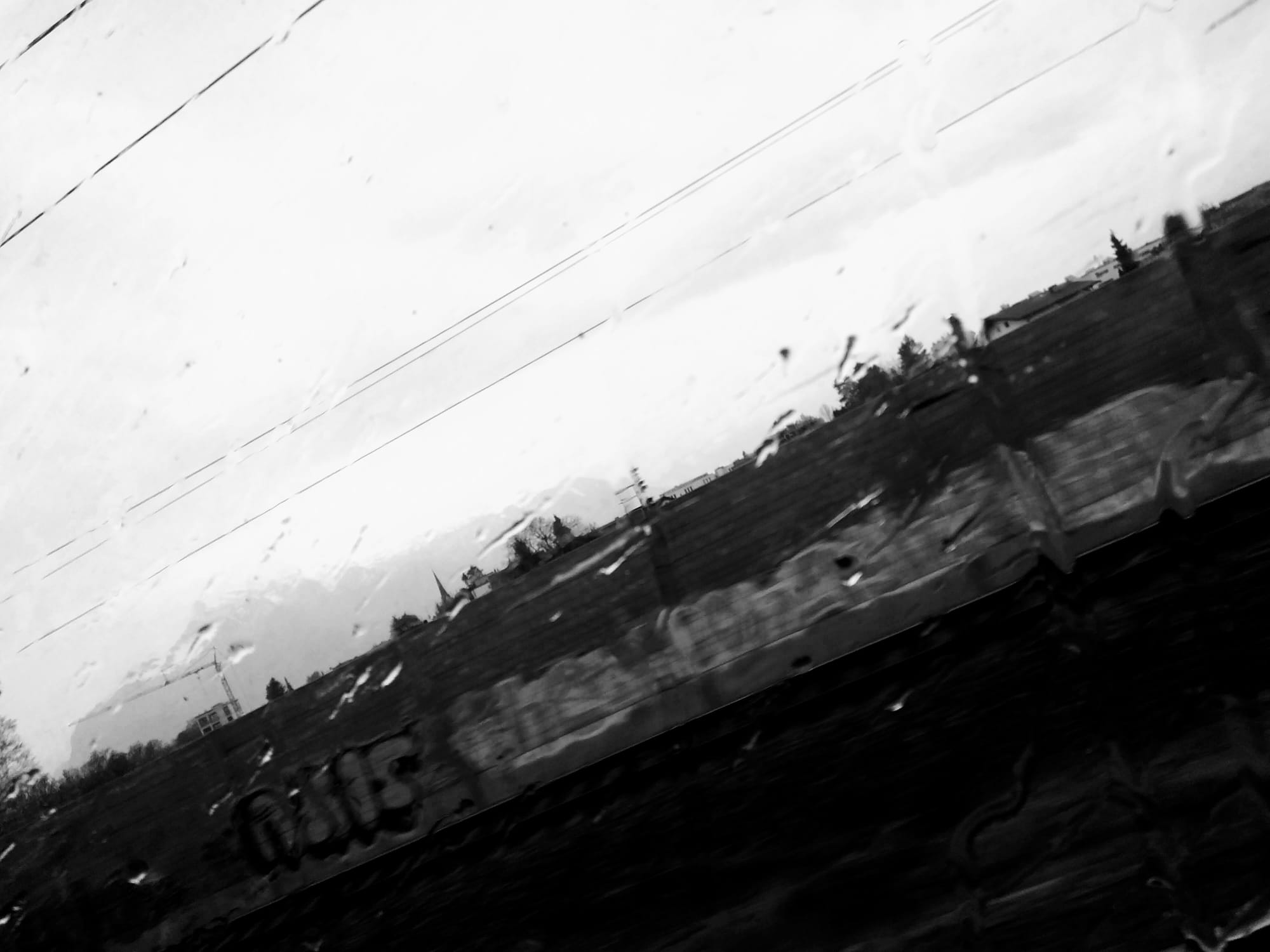 Graffiti on a wall seen through a rain-covered window. Black and white.