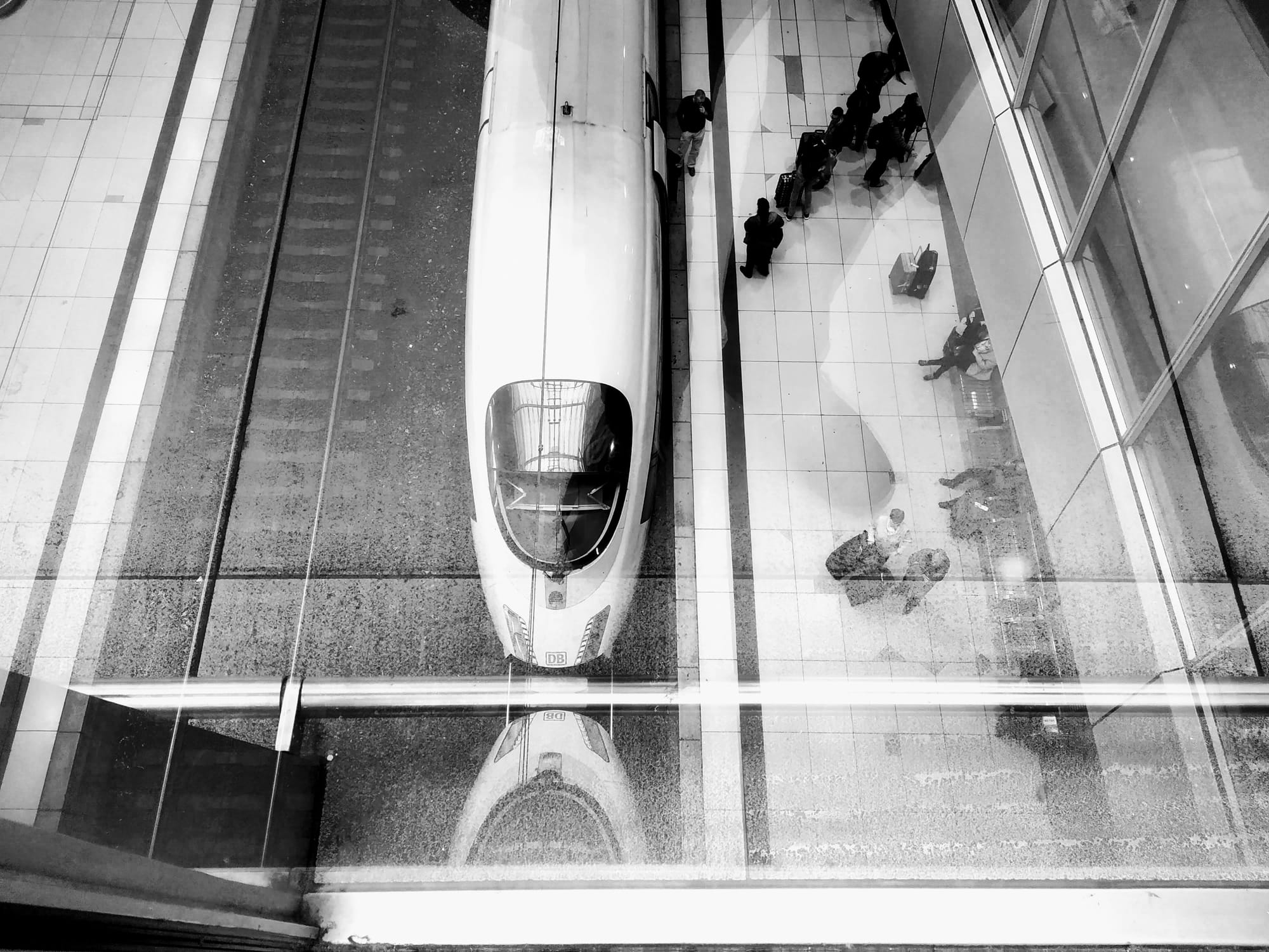 View from a footbridge over platforms of a waiting ICE and passengers.