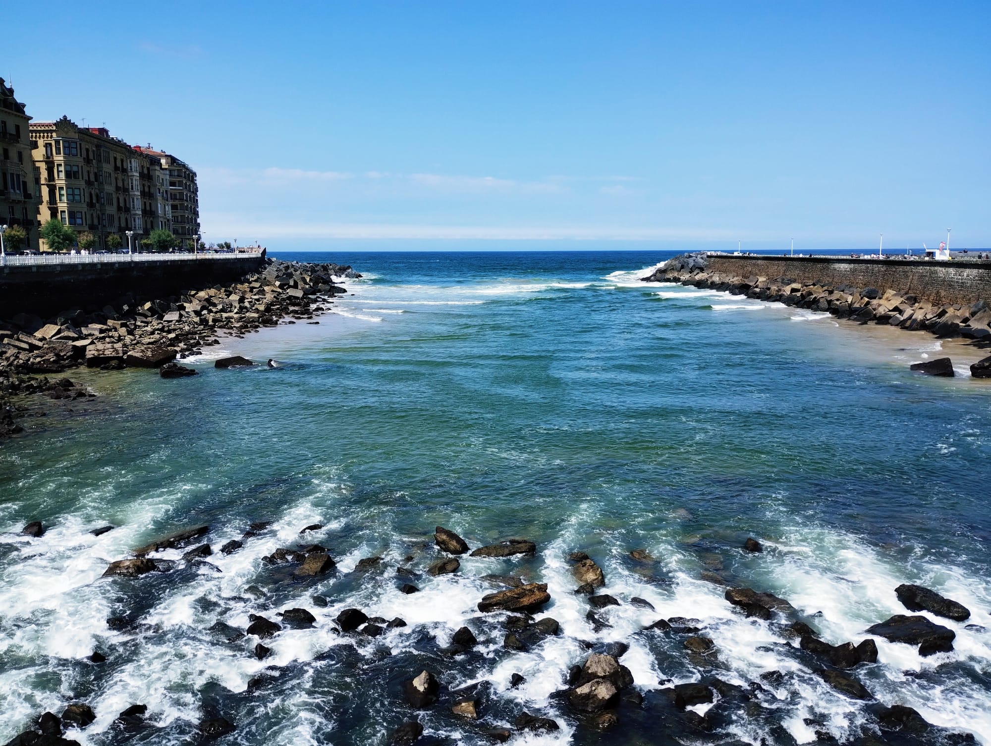 The Urumea River flows over rocks into the Atlantic Ocean.