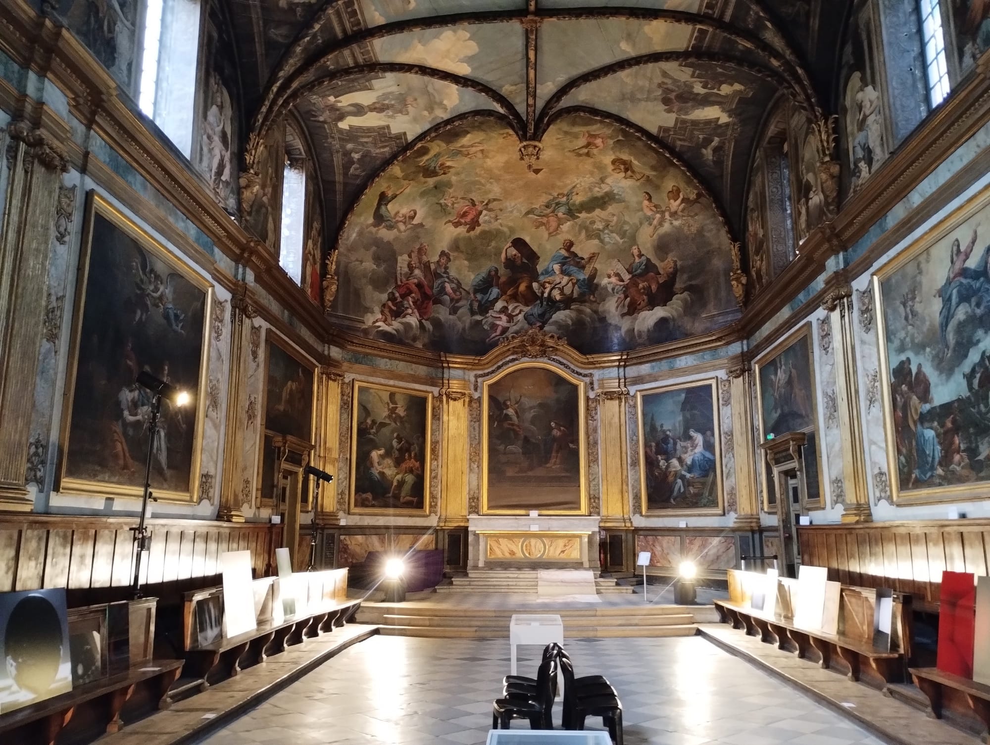 The interior an old chapel. Paintings and frescoes cover the walls and ceiling.