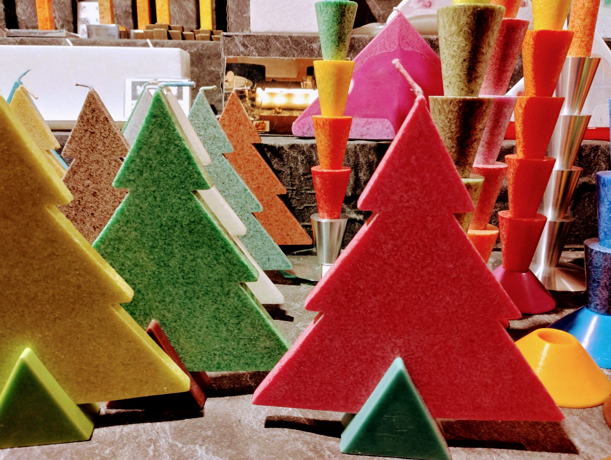 A selection of multi-coloured candles shaped as Christmas trees.