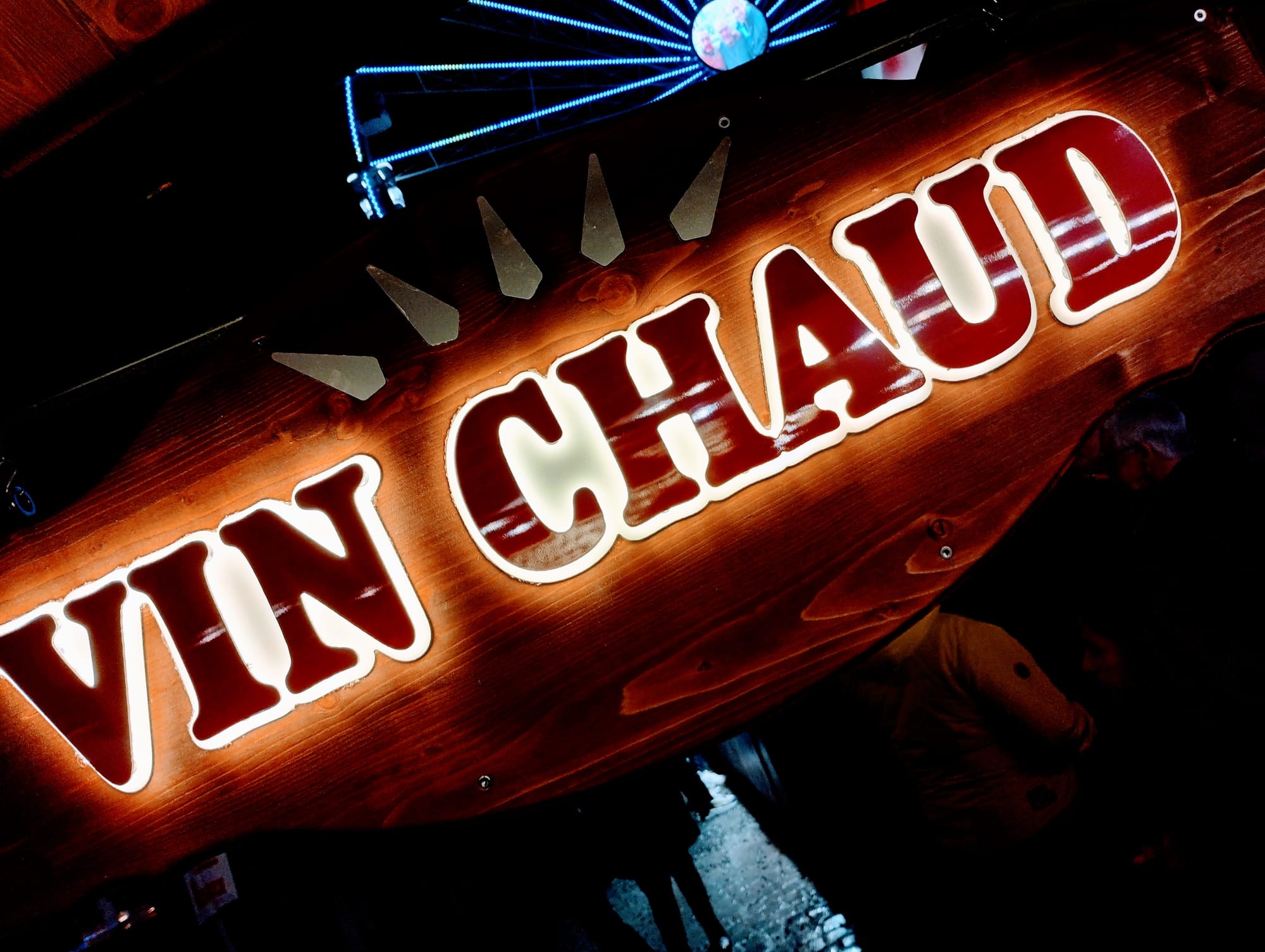 A close-up of an illuminated sign for "vin chaud".