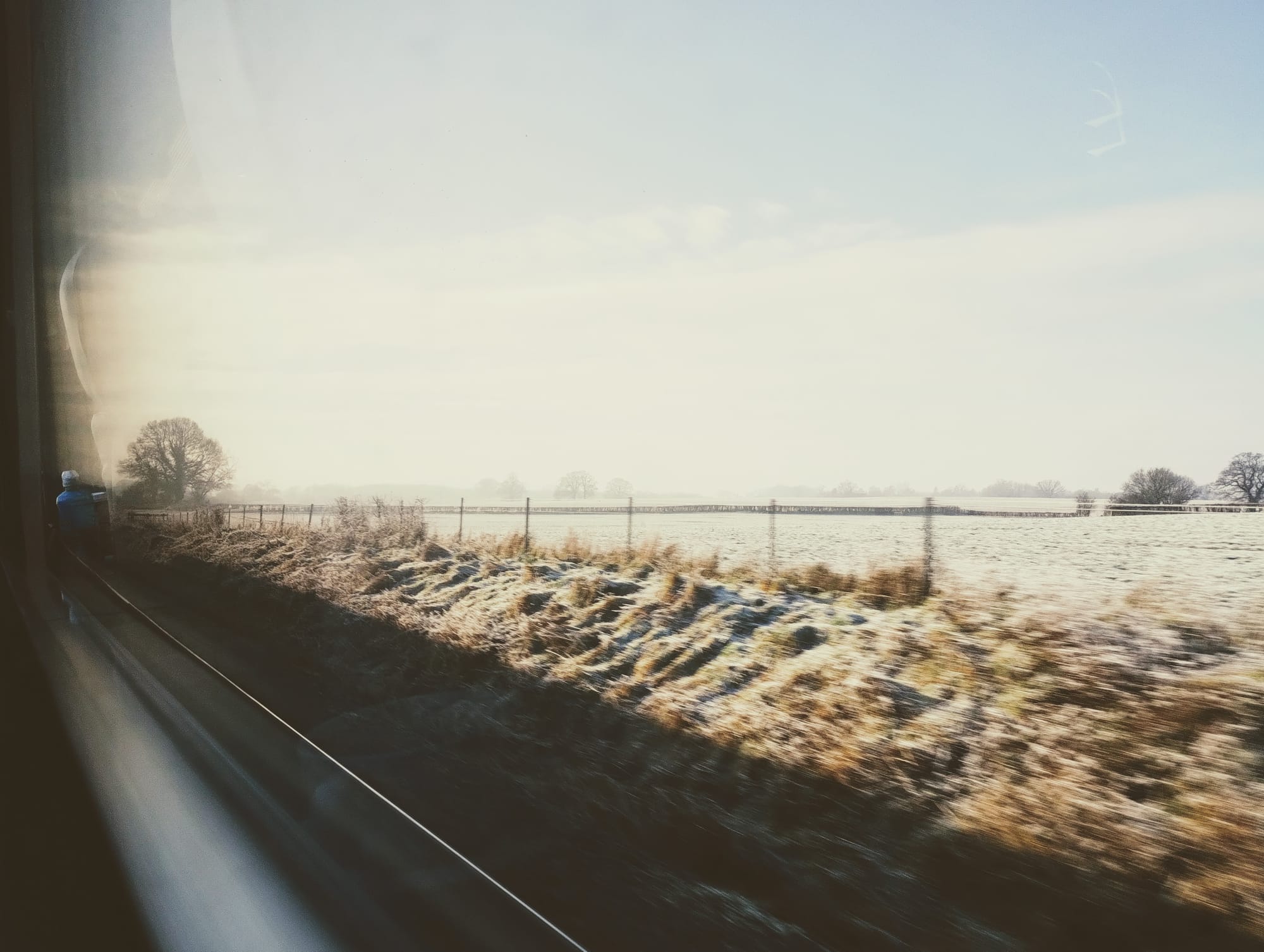 Frosty fields blur past a train window.