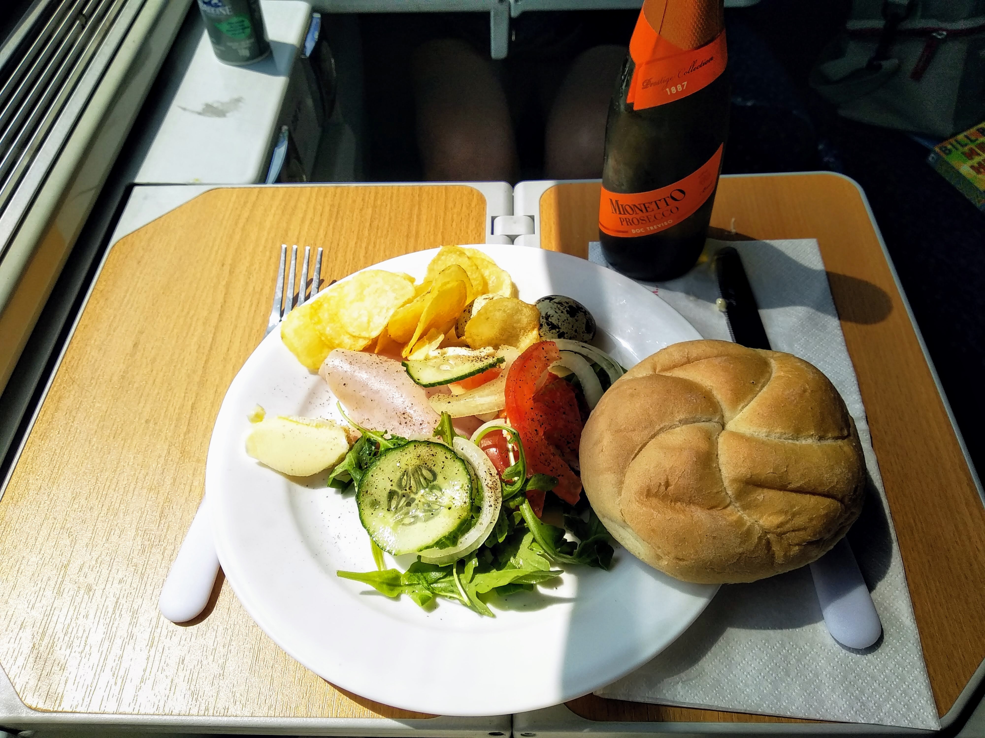 A plate of ham salad, crisps, and a bread roll. The salad is made palatable by the presence of a baby bottle of Mionetto Prosecco.