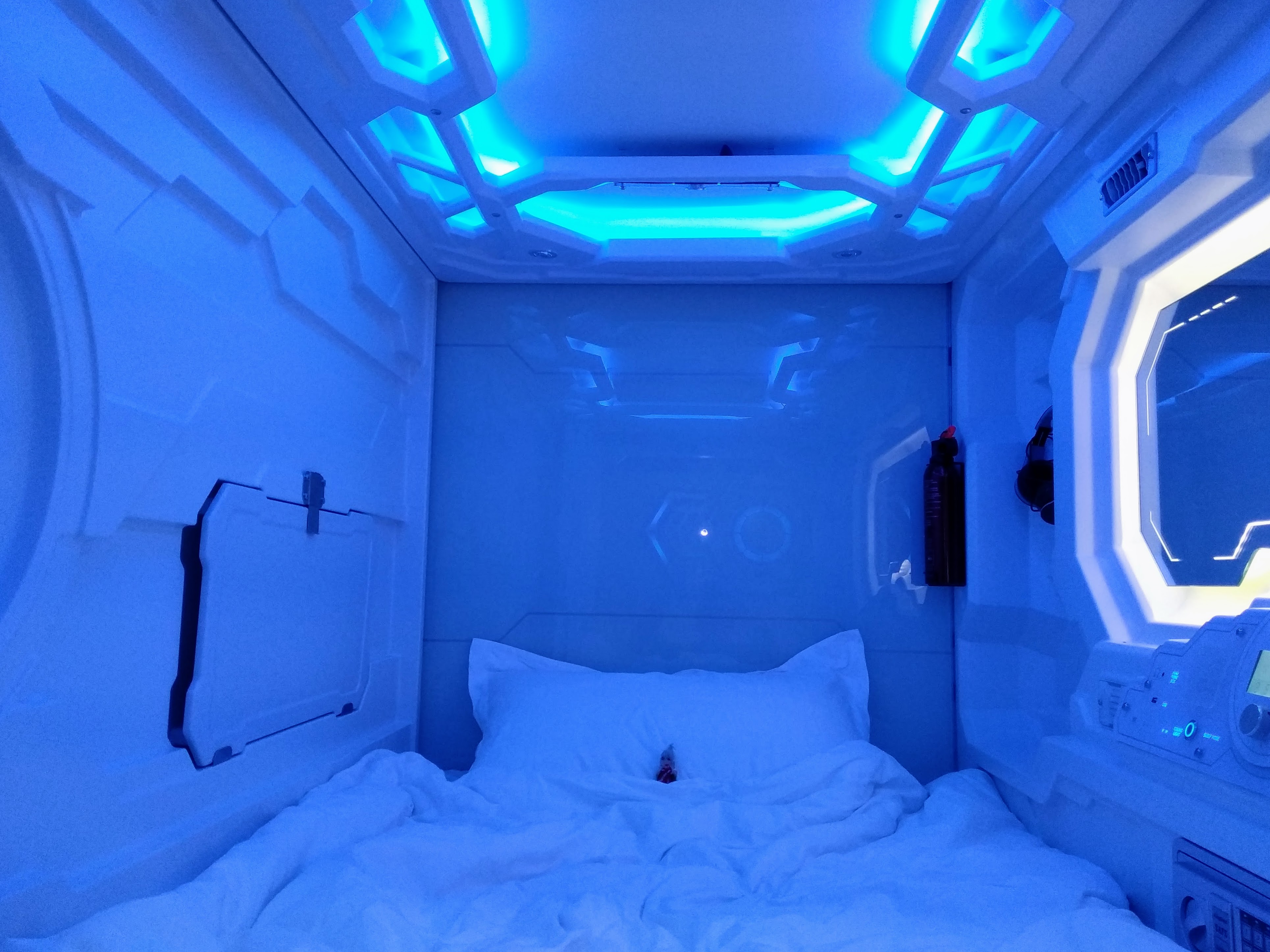 The futuristic interior of a gaudy blue sleeping pod.