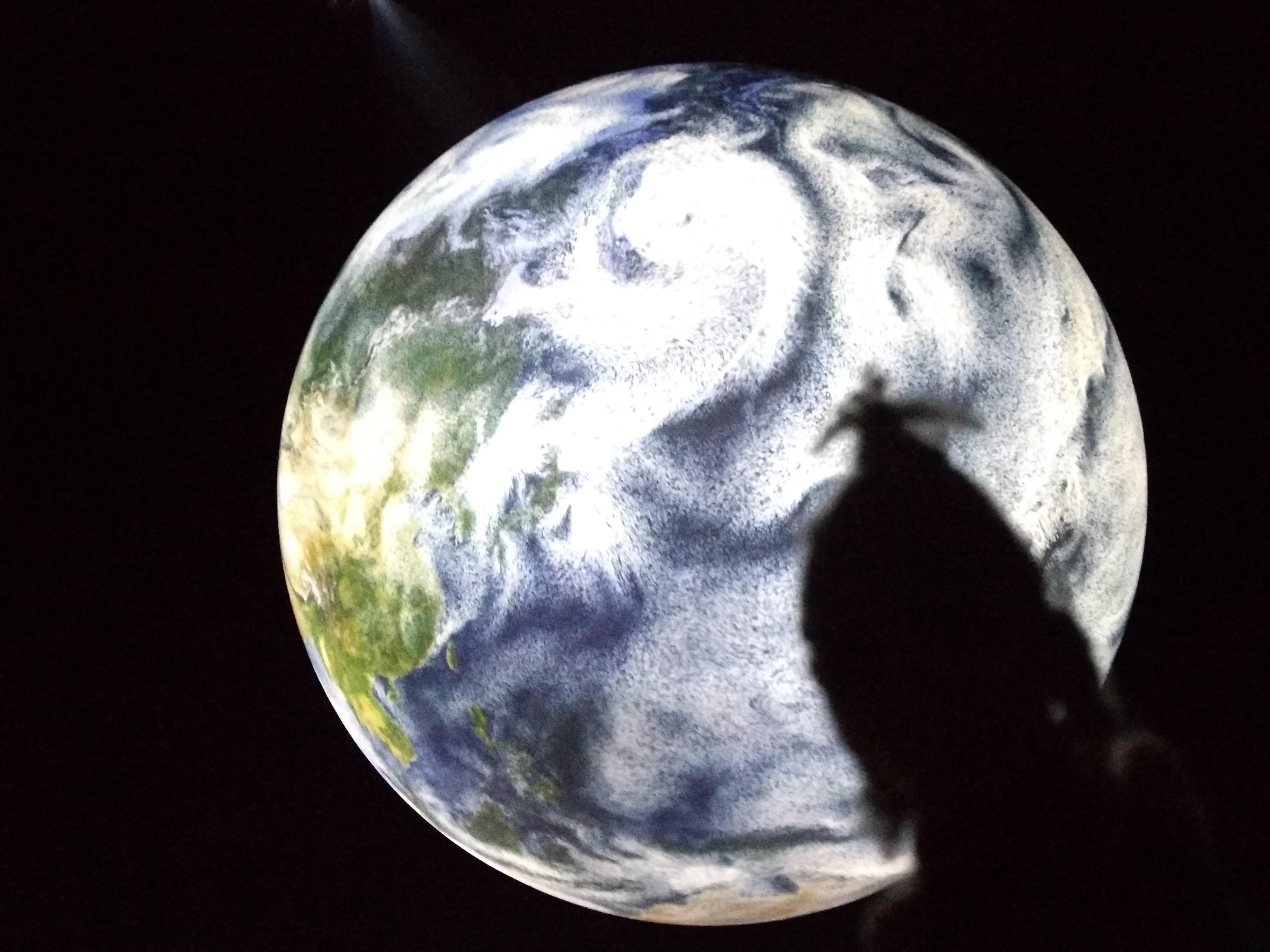 Silhouette of a puppet in front of a projection of the Earth.