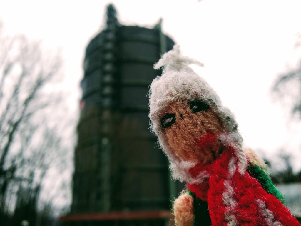 Puppet in front of an old gas storage tower.