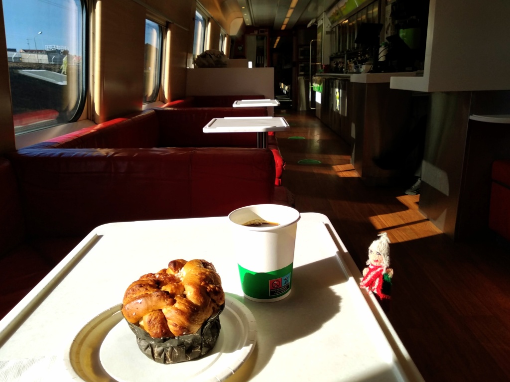 Puppet enjoying a cake and a coffee in a sun-drenched bistro compartment.