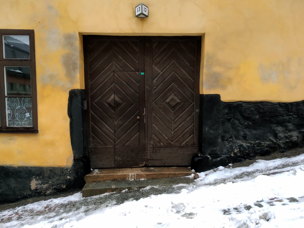A brown wooden door, number 13, set in a pastel yellow wall.