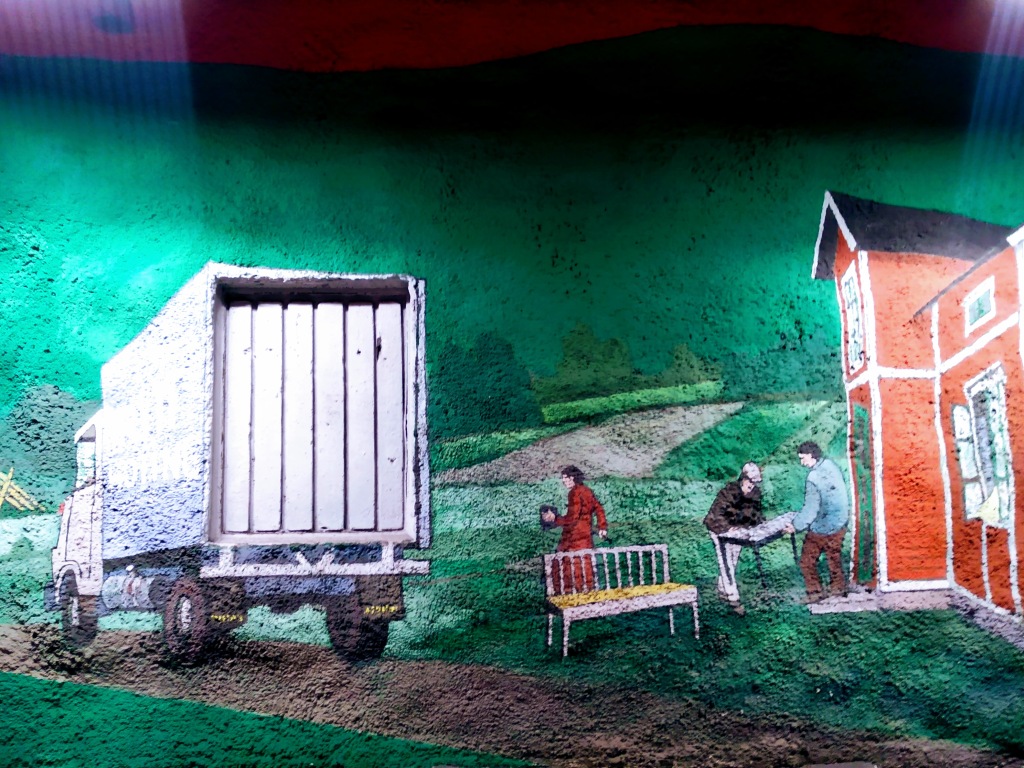 An access point in a wall forms the back of a lorry in a scene where people are moving house.