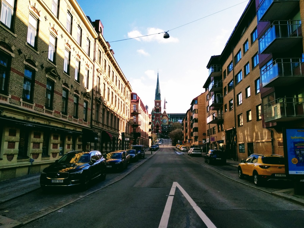 Cars and buildings line the street to a church.