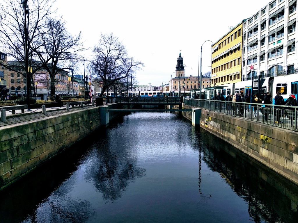 A white and blue tram crossing a bridge over a canal.
