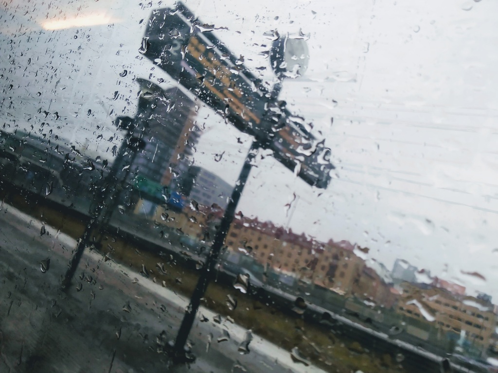 Rain on a train window obscures the station platform behind
