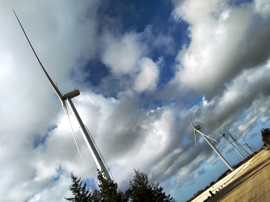 A row of wind turbines against a cloudy sky at the Østerild wind turbine test field.