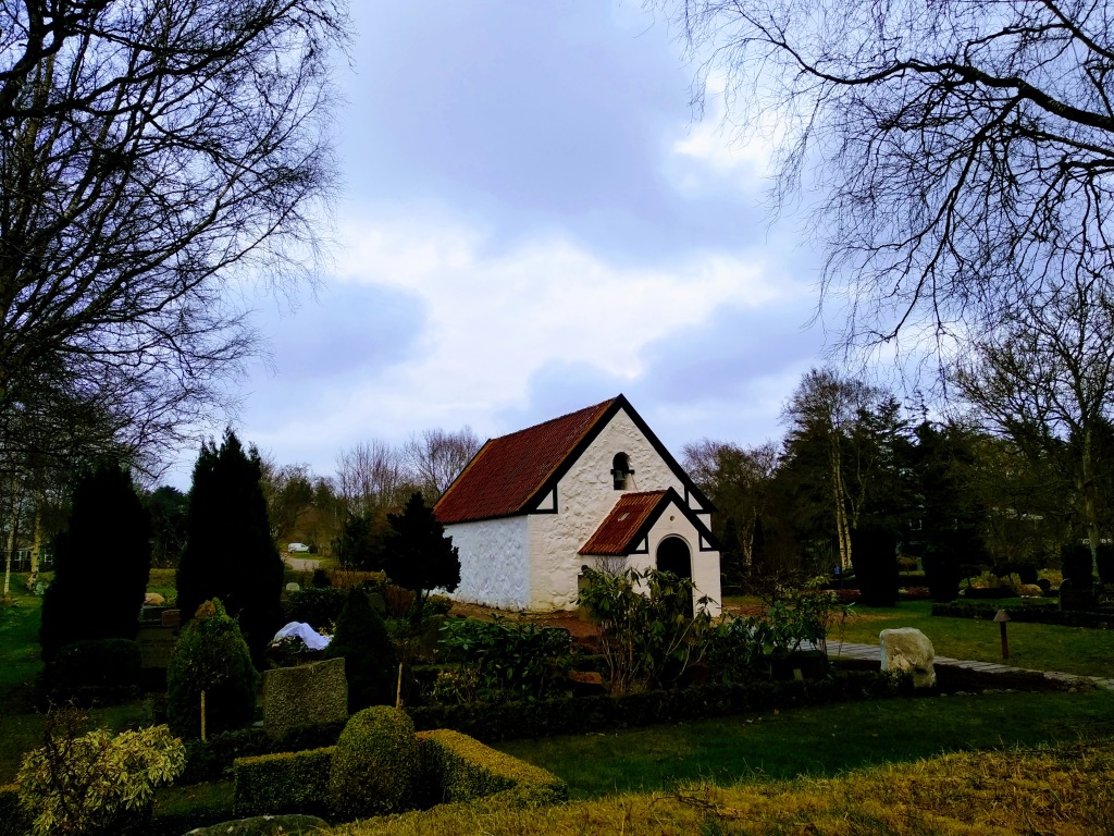 A small stone church in Venø and some of the graveyard surrounding it.