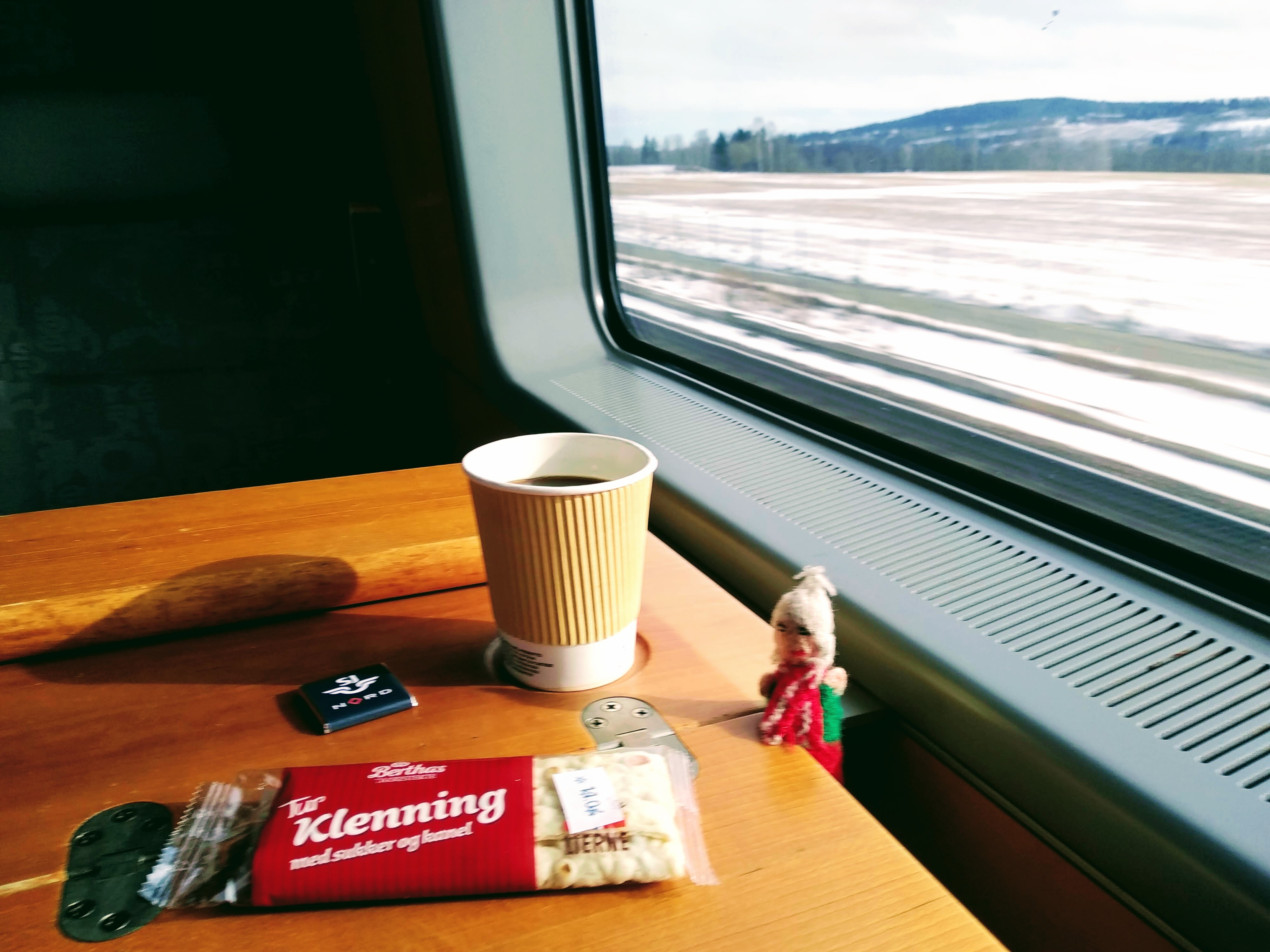 Puppet enjoys breakfast in front of a snowy view through a train window.