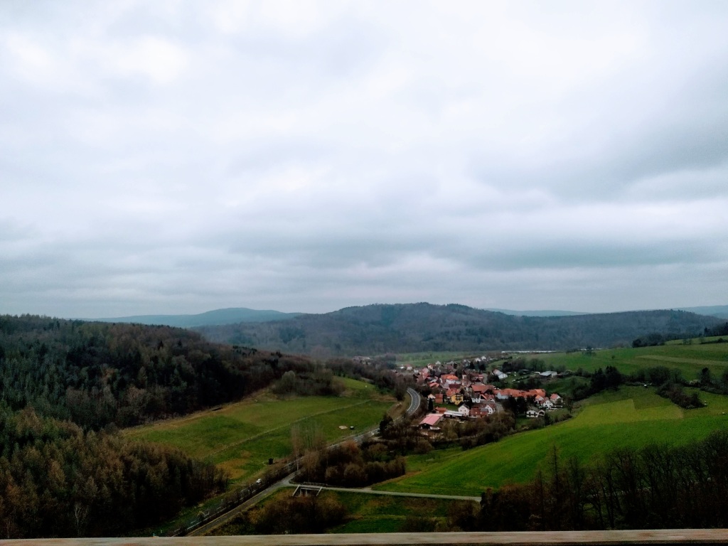 View from a train window of a village nestled in a green valley.