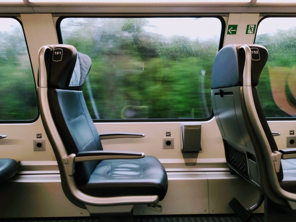 Green trees blur past a rain-covered window next to see 161 on a German train.