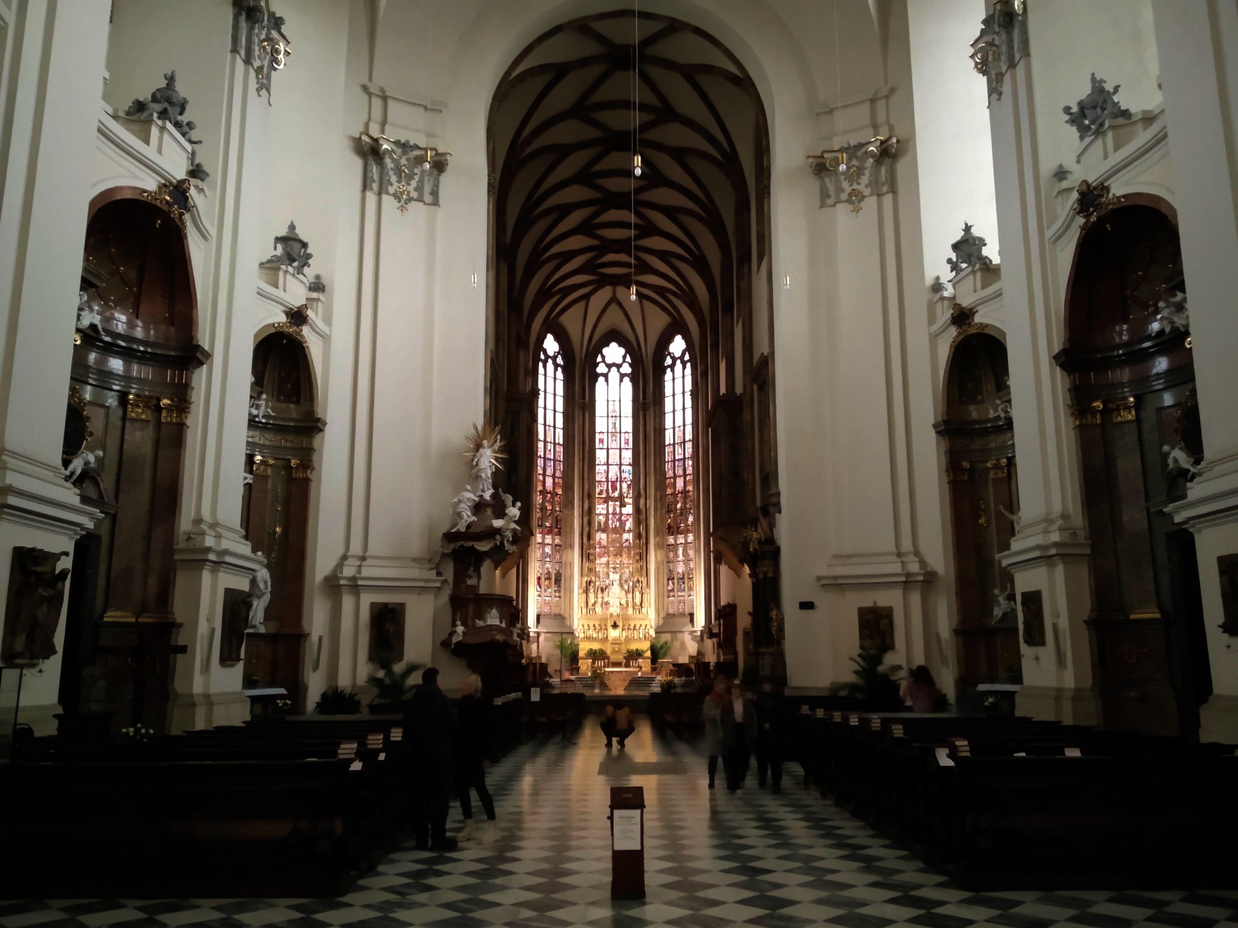 Looking down the nave of the Cathedral of St. Peter and Paul towards the illuminated chancel and its stained glass windows.