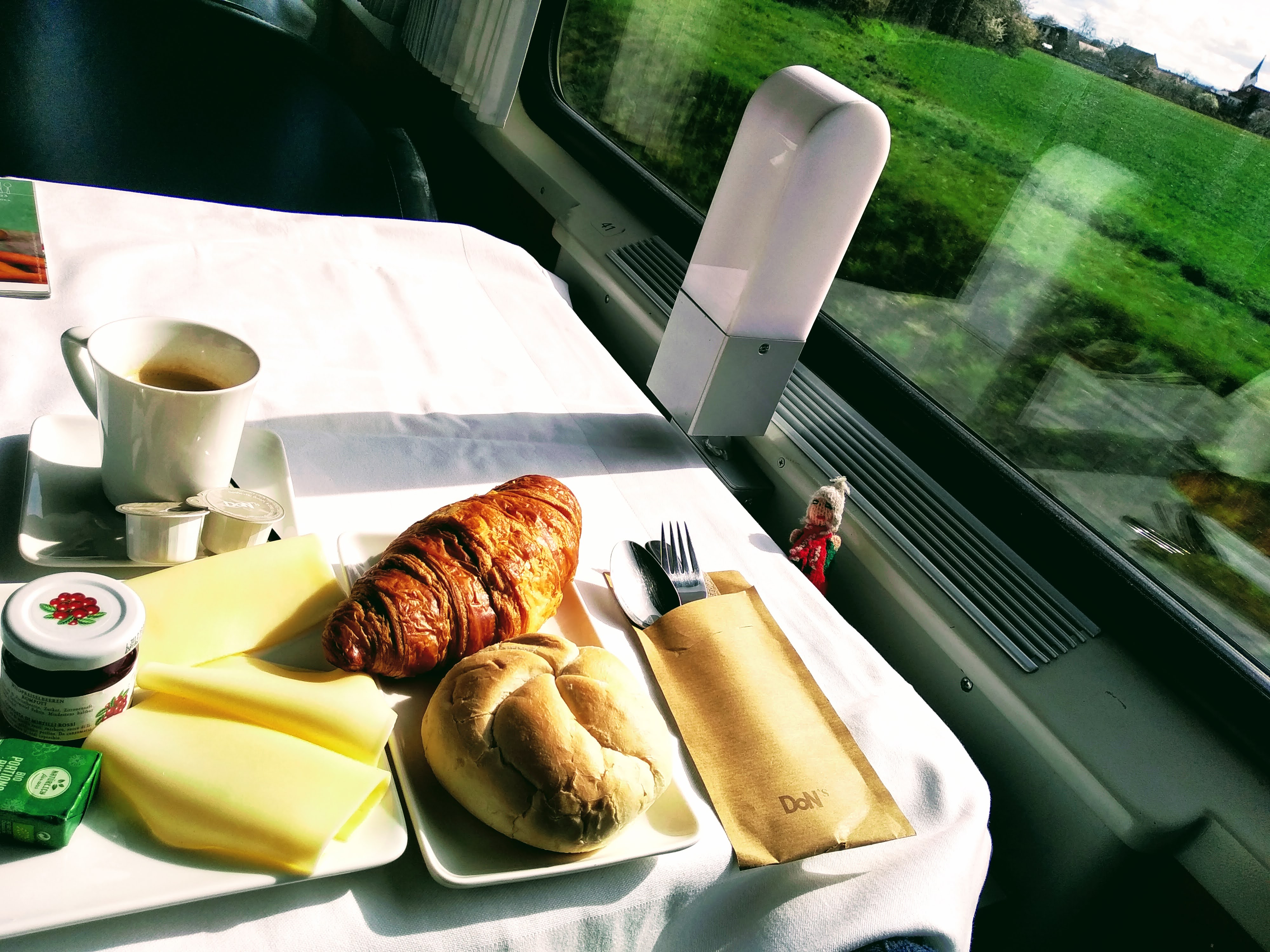 Coffee, croissant bread, cheese, butter and jam in a dining car. And a pupppet.