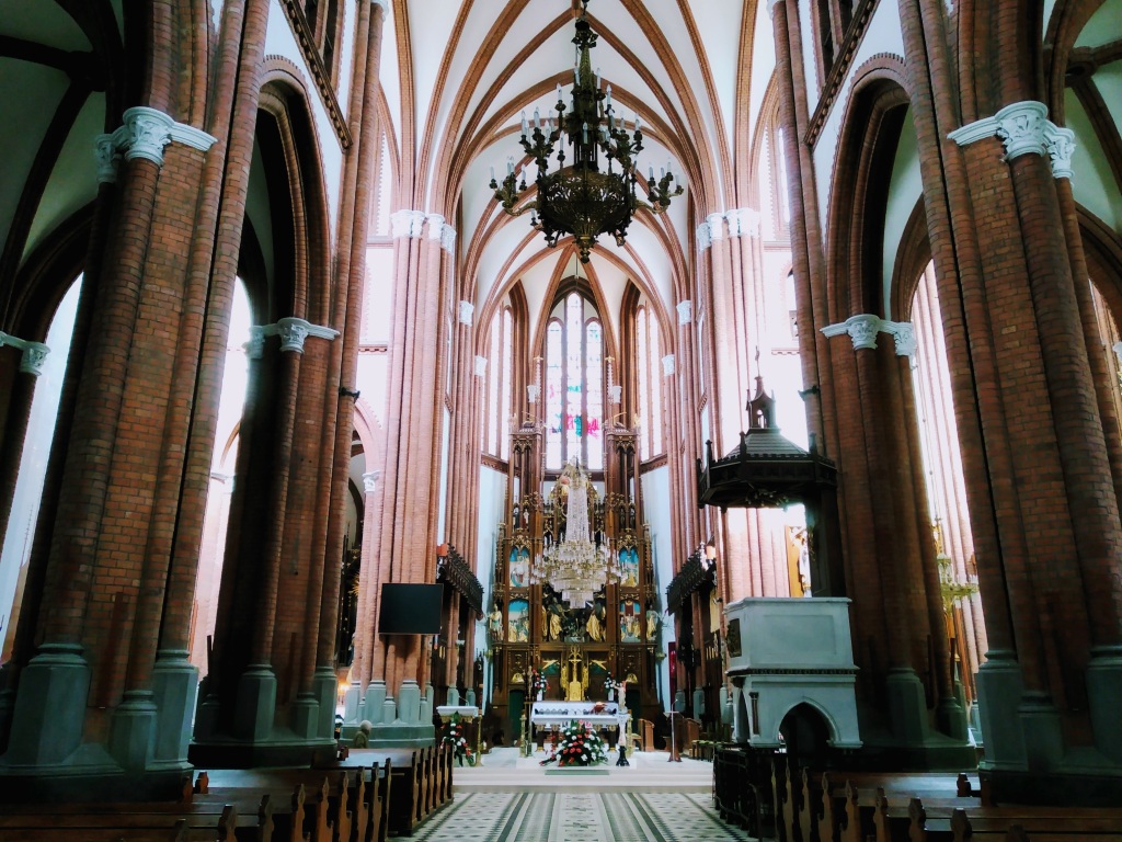Looking down the nave of a church towards the altar, with brick pillars either side.