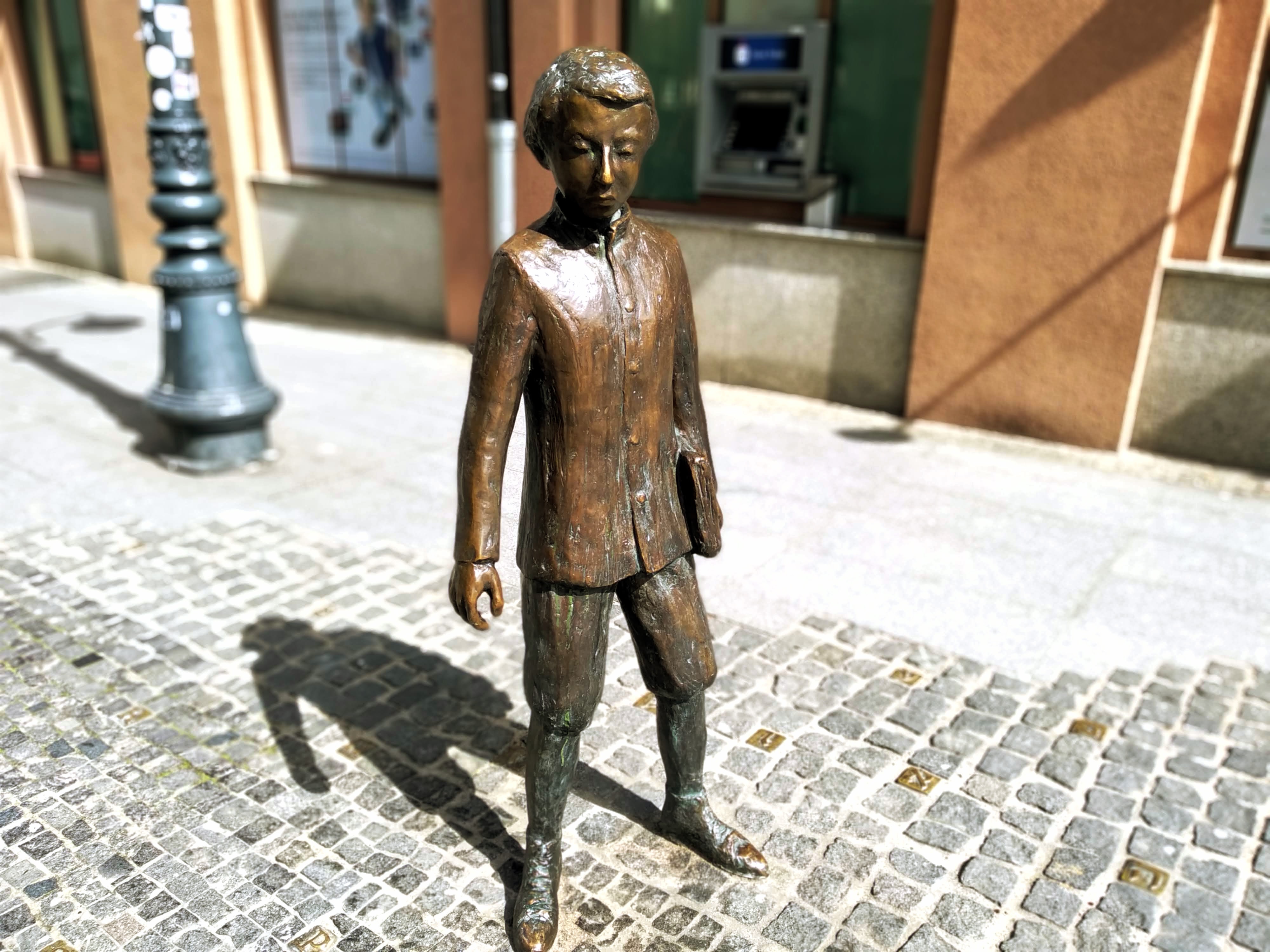 A small bronze statue of a young Ludwik Lejzer Zamenhof holding a school book under his left arm.