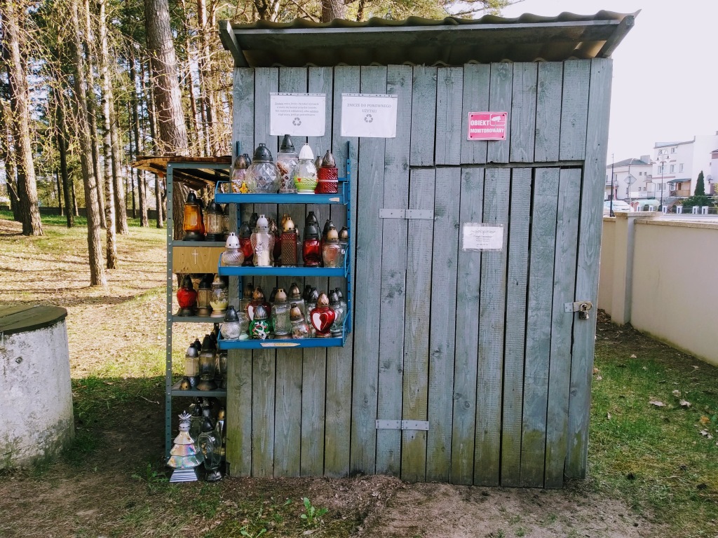 A small wooden shack offering tat for graves on shelves, with a simple padlocked door.
