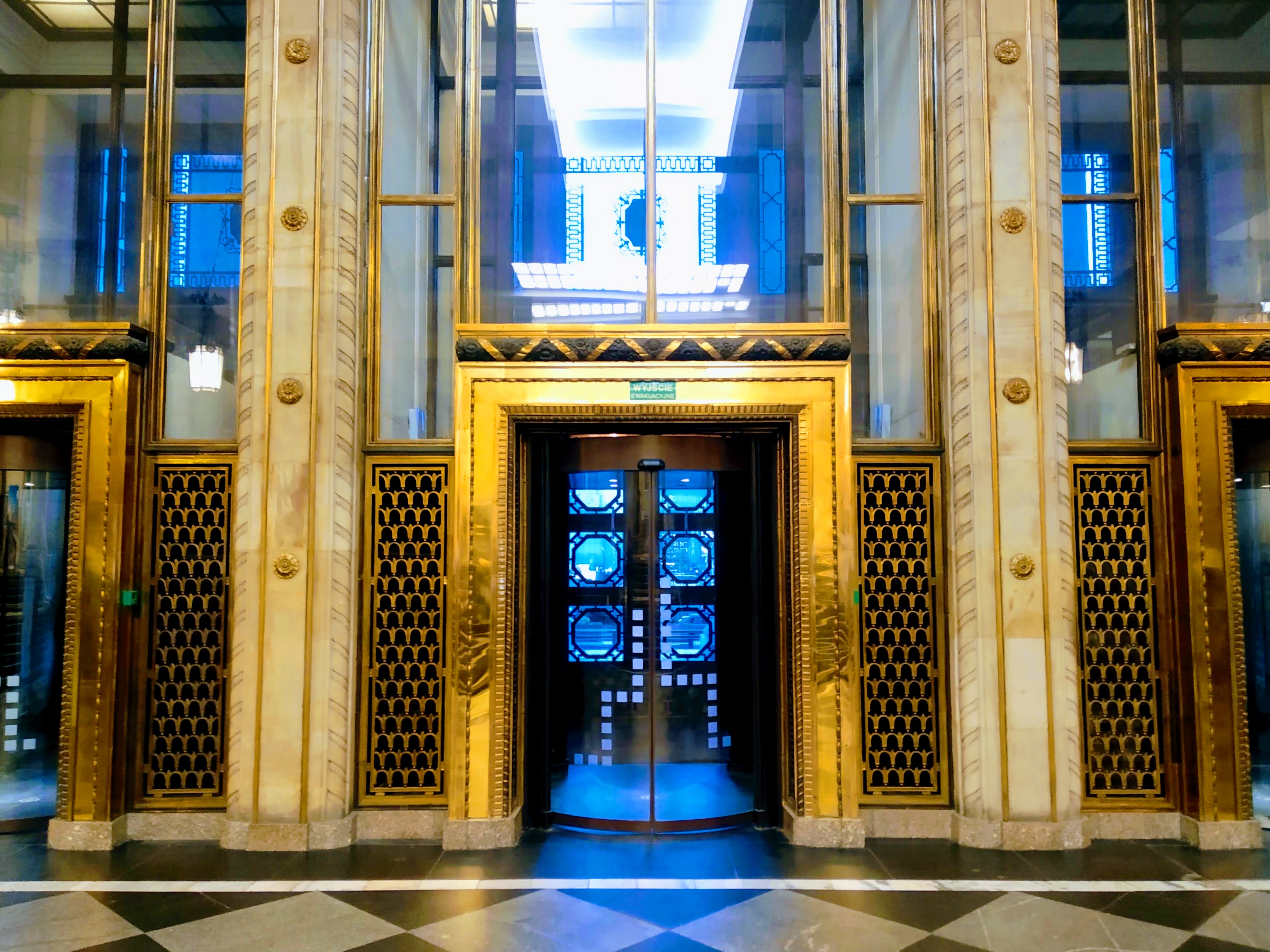 Photograph of a shiny door between two pillars inside the Warsaw Palace of Culture and Science.