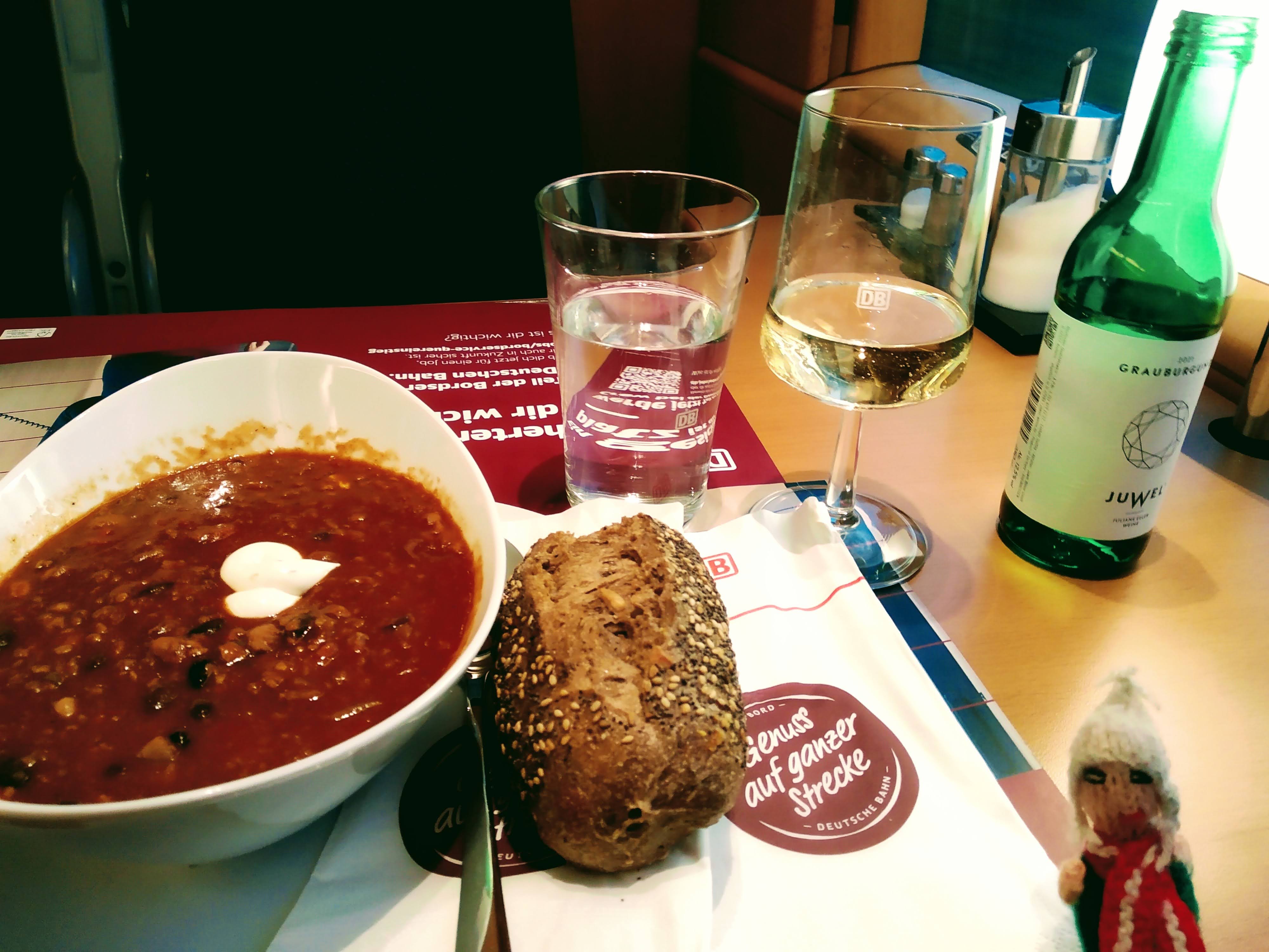 Chili sin carne, bread roll, wine, sparkling water, puppet. In a dining car.