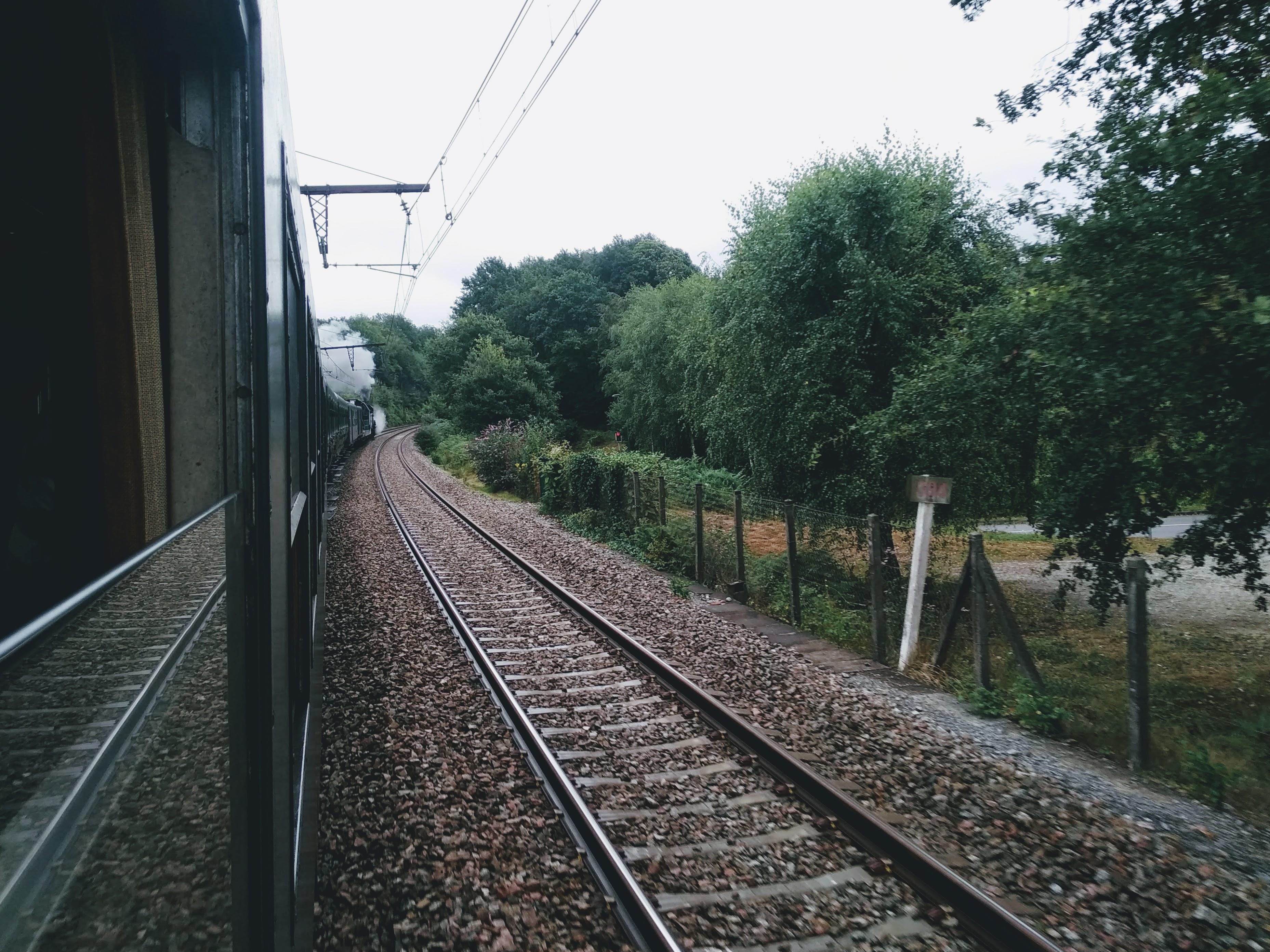 A view from a rear carriage of a steam train, looking towards the locomotive.