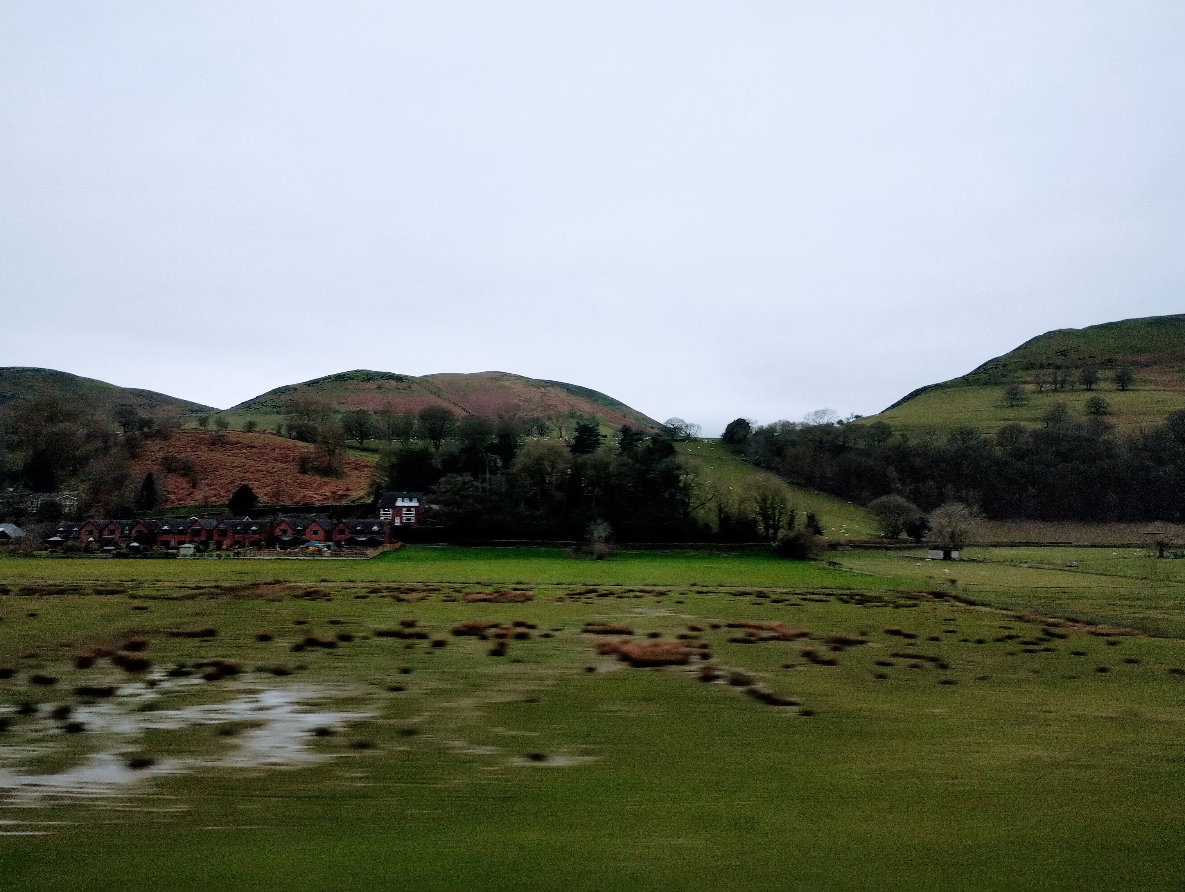 Shropshire hills and moist fields pass a train window.