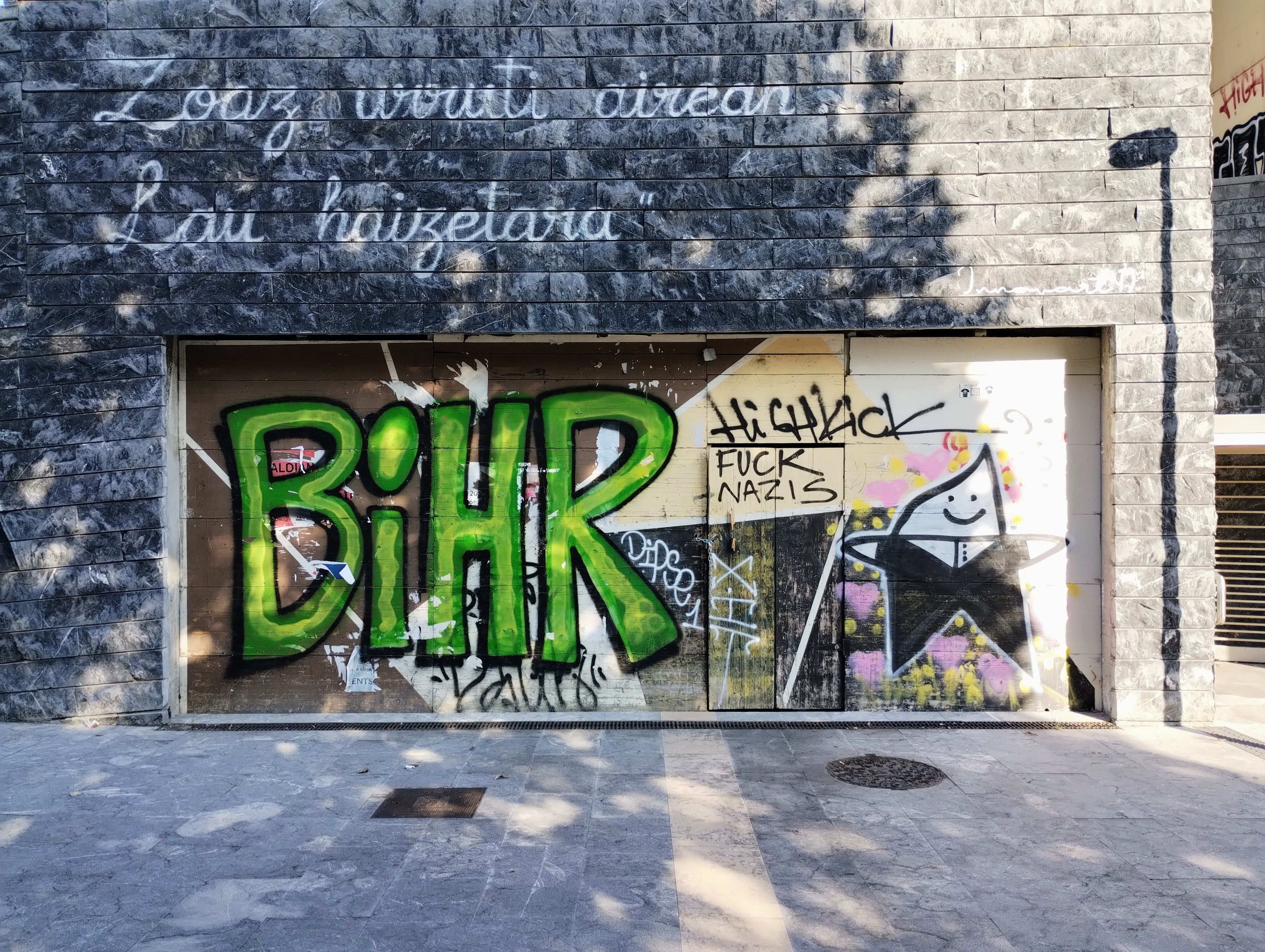 A door in a stone wall is covered in graffiti that reads "Fuck Nazis"