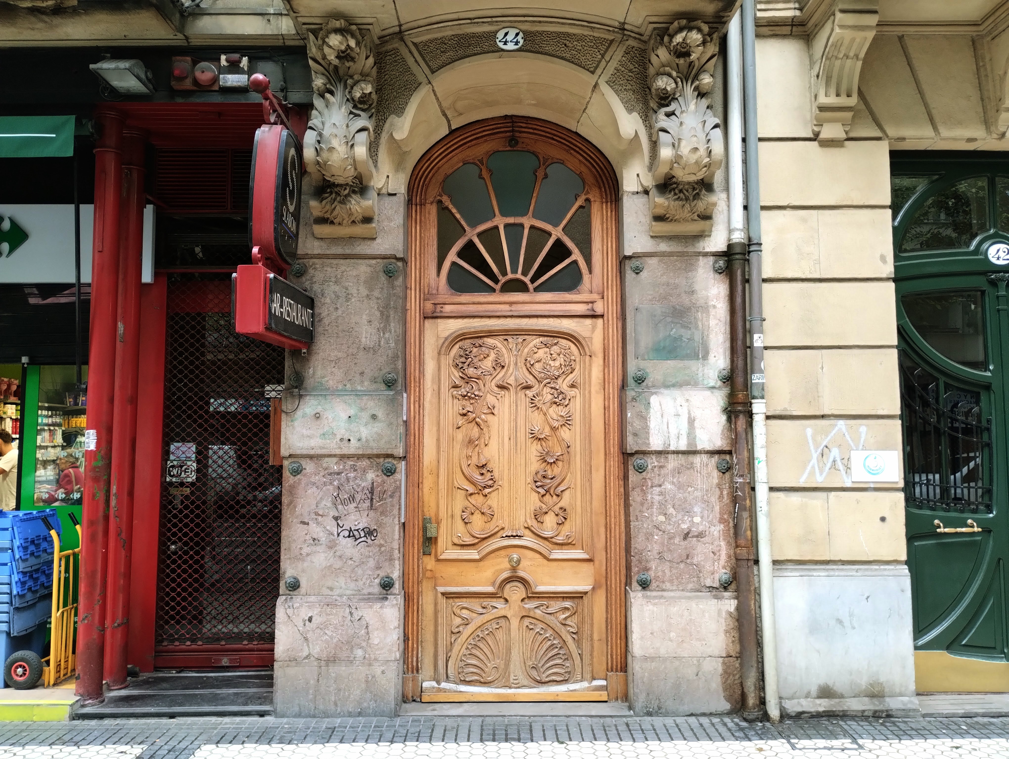 An ornate wooden door with fanned vasistas in a stone wall.