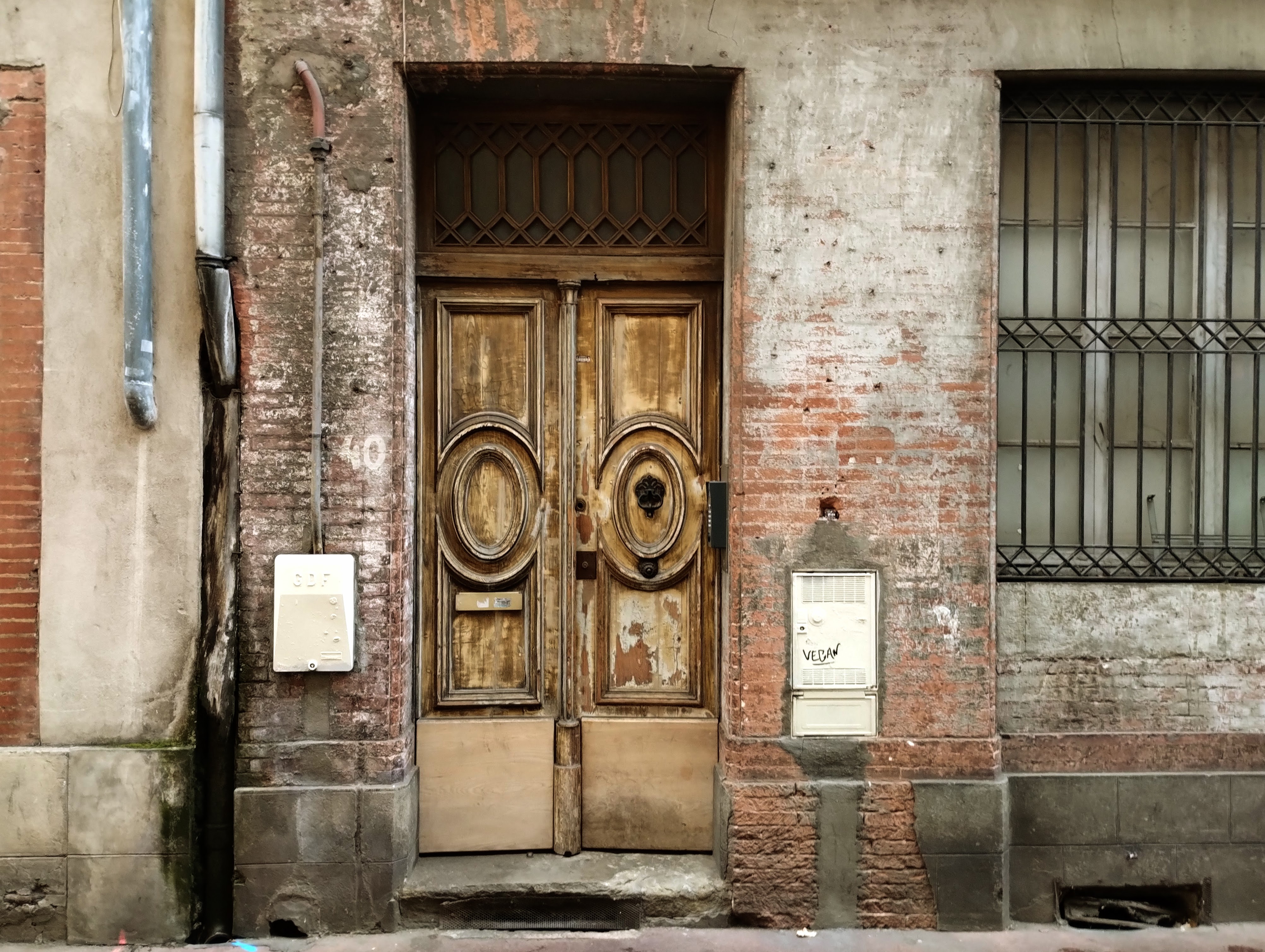 A tired wooden double door set in a red brick wall.