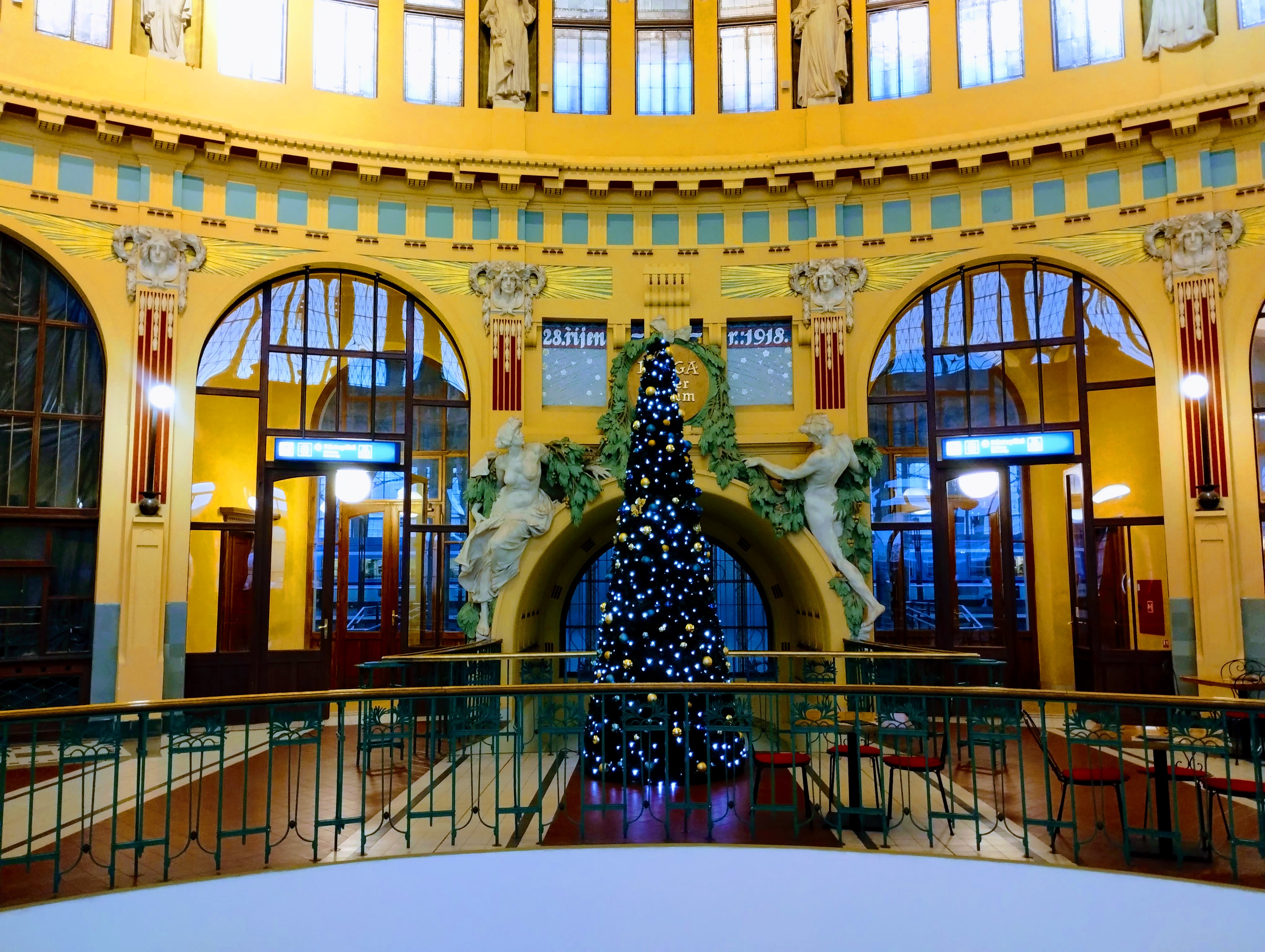 The Christmas tree illuminated with simple white lights under the dome in the old part of Prague's main railway station.
