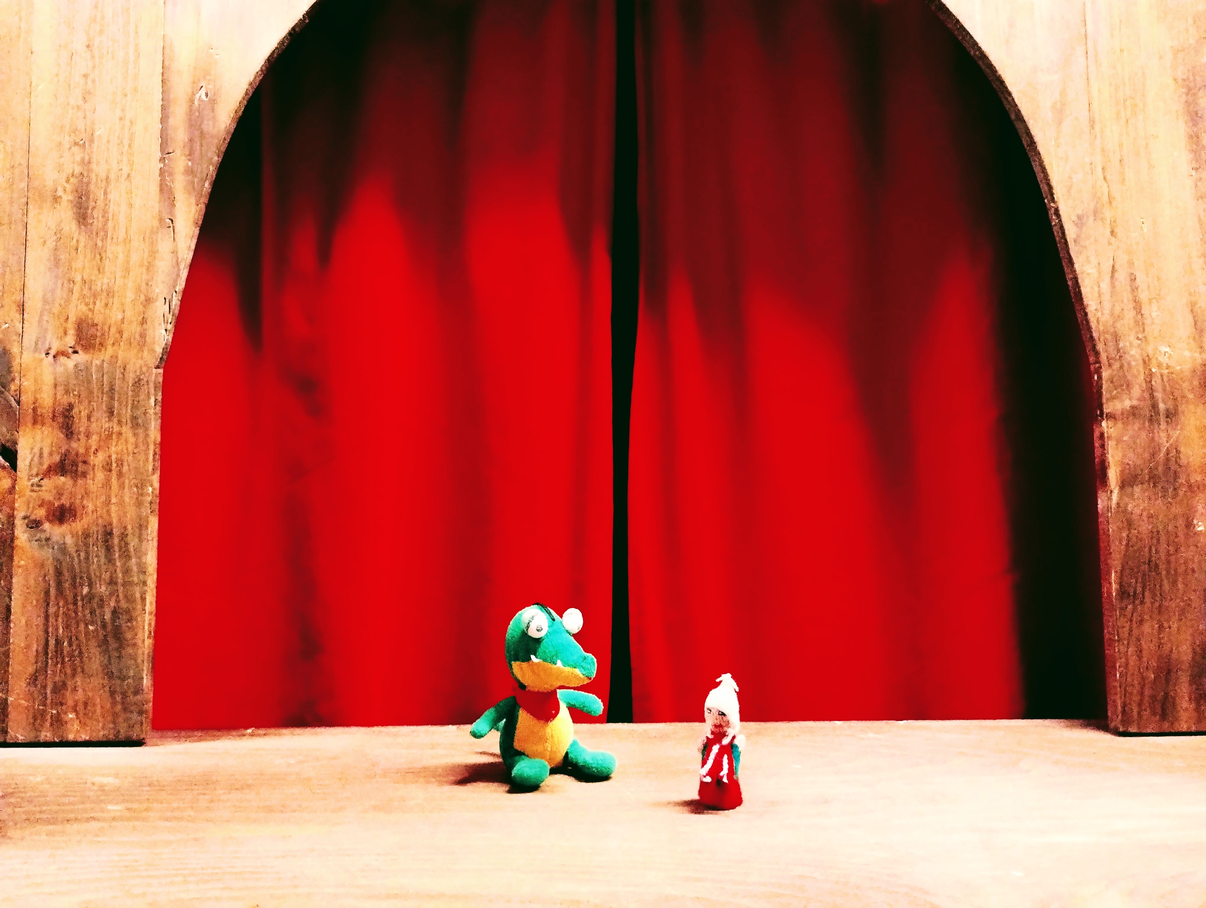 A Peruvian finger puppet and an adorable fluffy dragon share the limelight on-stage in front of a red curtain.