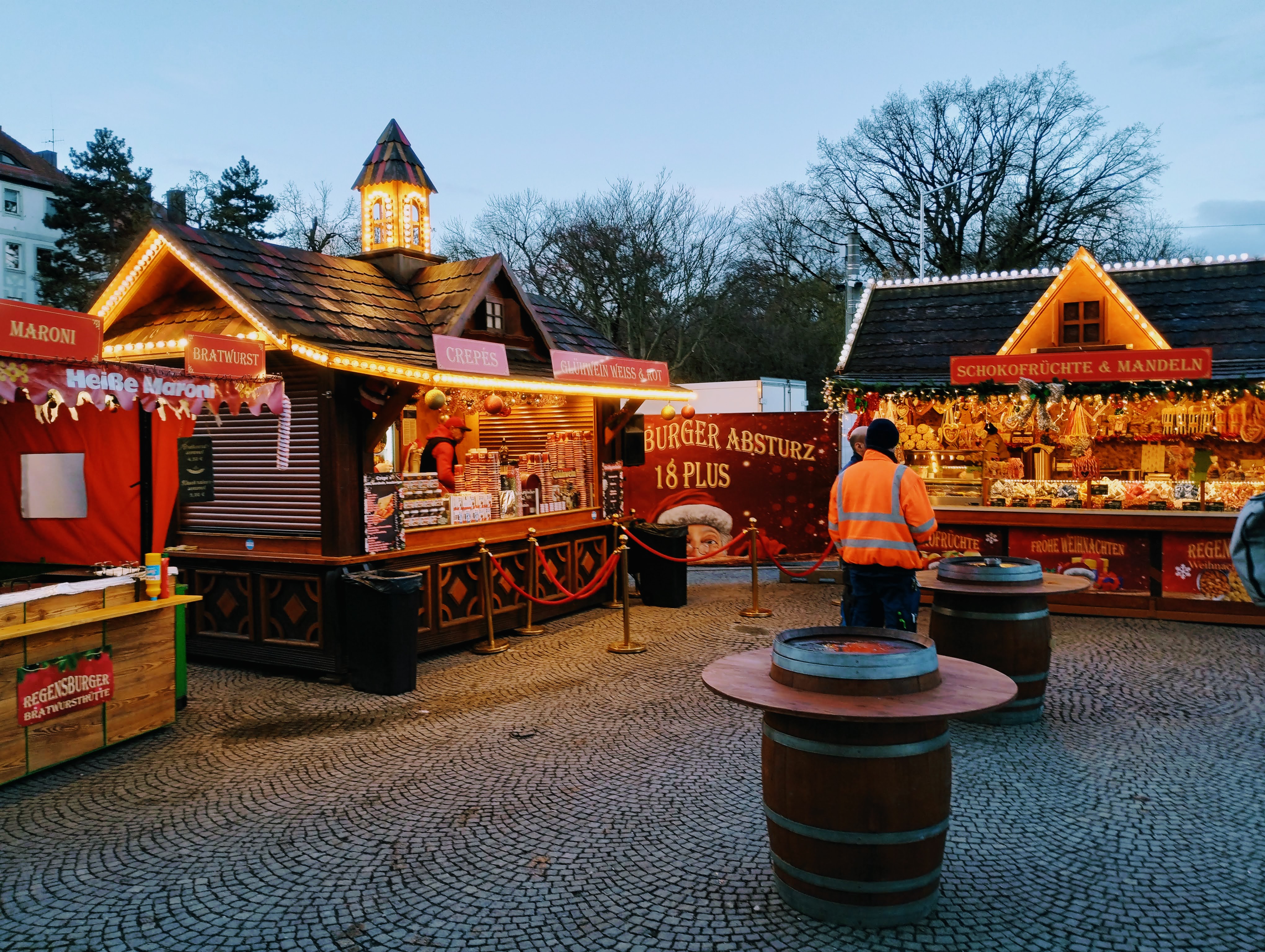 A small Christmas market with four stalls and two tables.