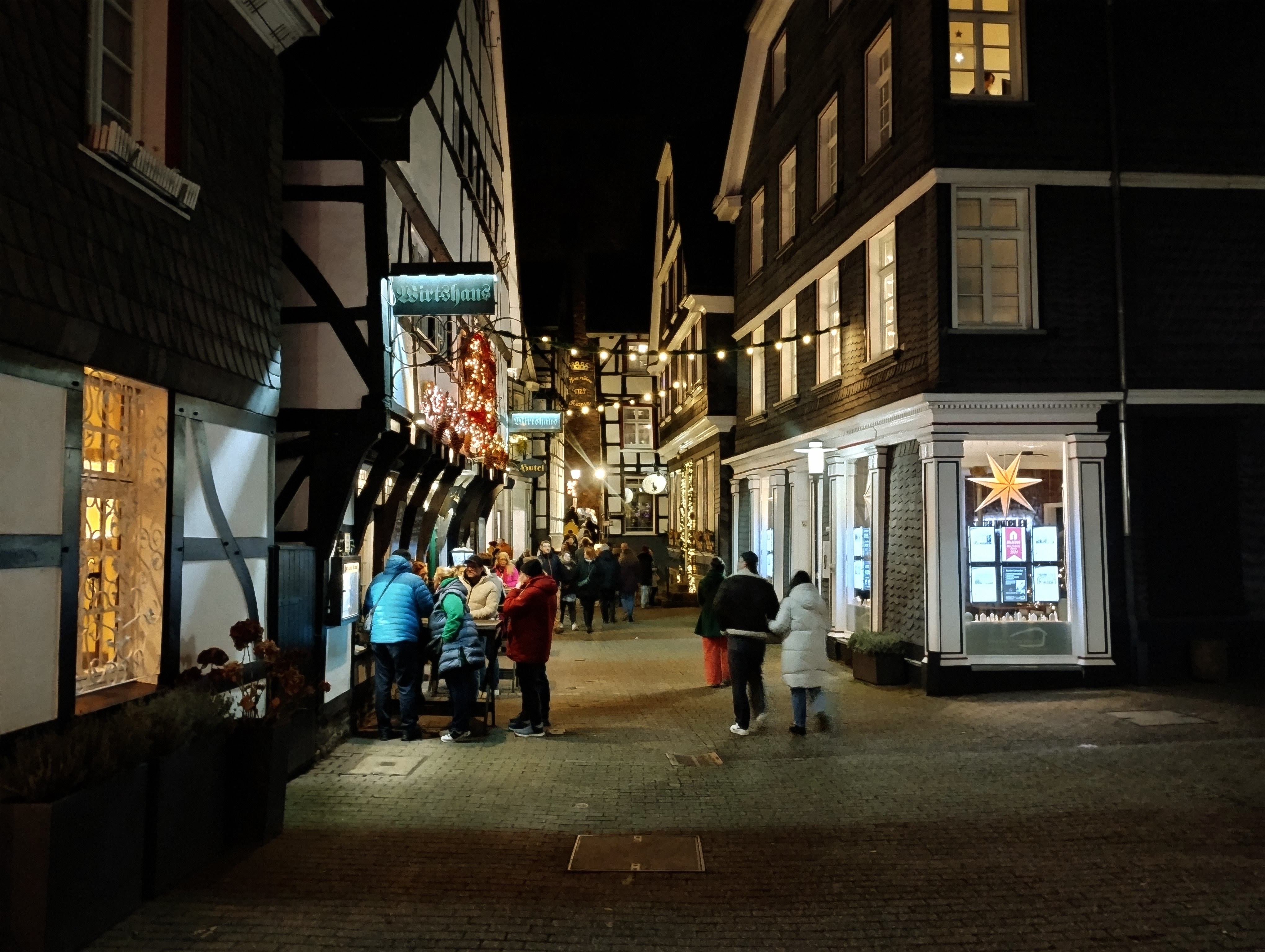 People stand around the entrance to a bar in a German town.