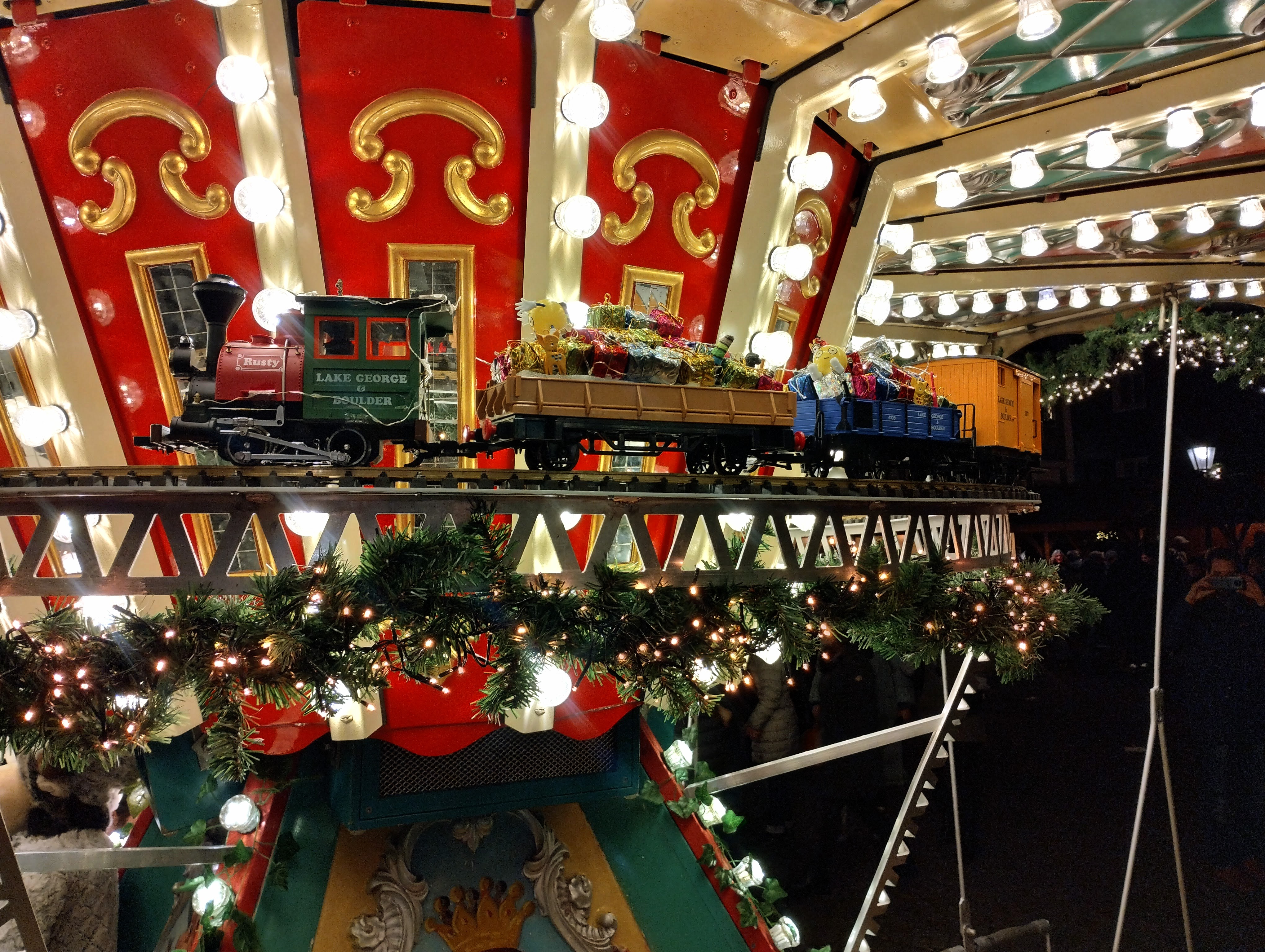 A model Christmas freight train pulls presents around the centre of a fairground carousel.