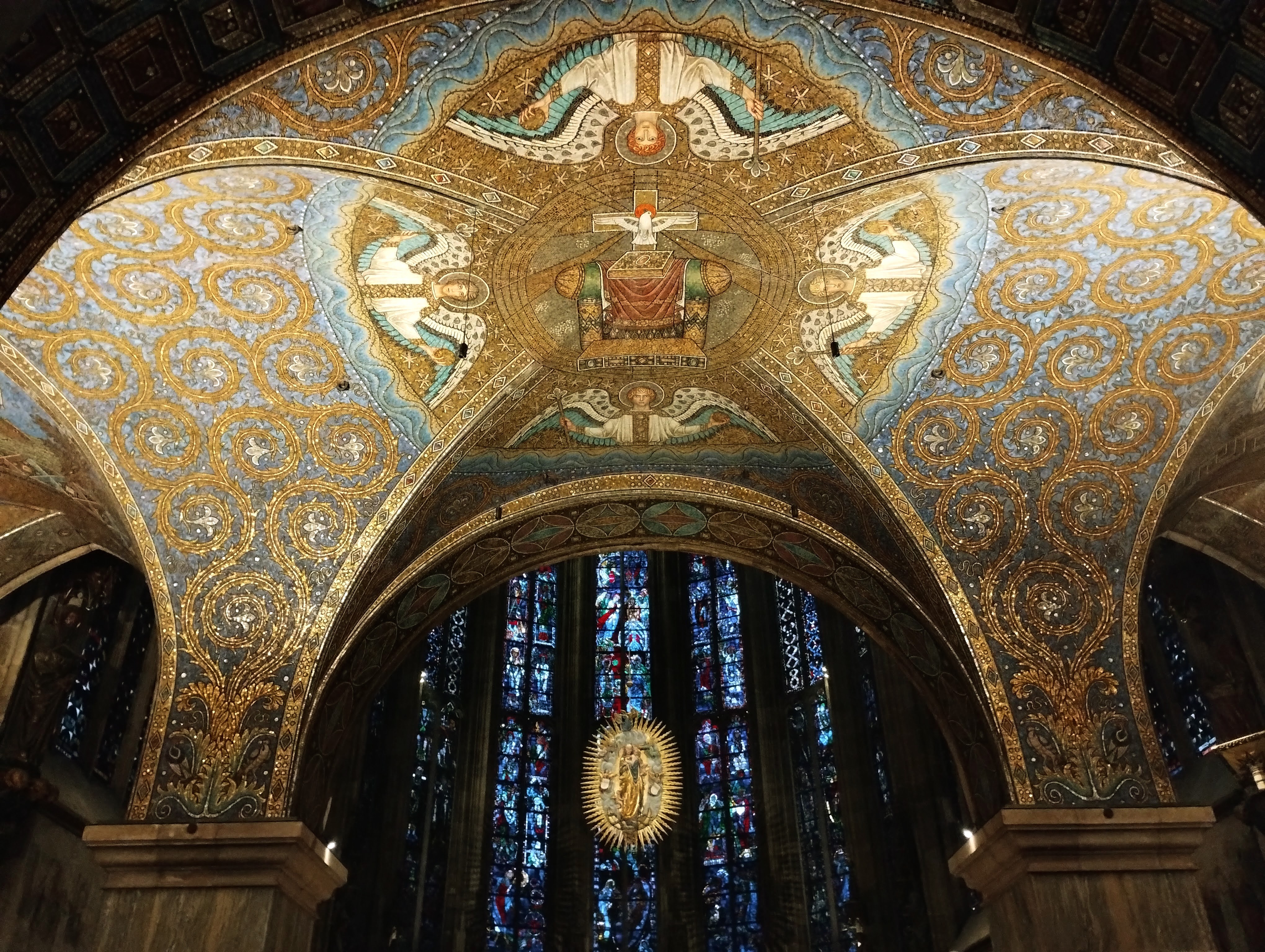 One of the ornately decorated roofs of the octagon and the stained glass behind it at the east end of Aachen cathedral.