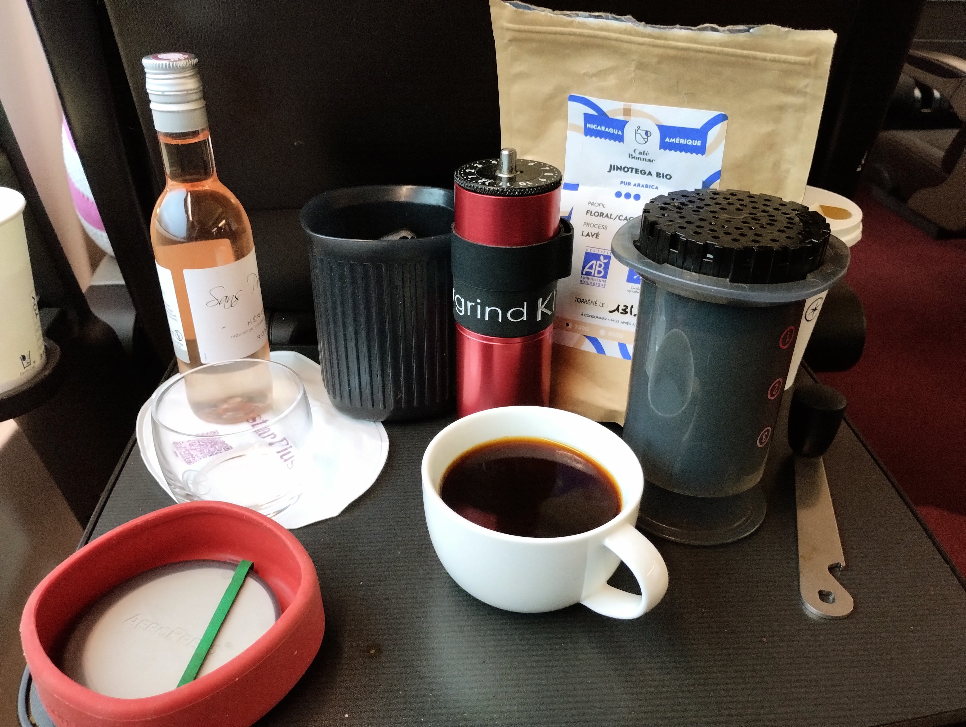 A brewed cup of coffee and the Aeropress, coffee, and beans required to make it.