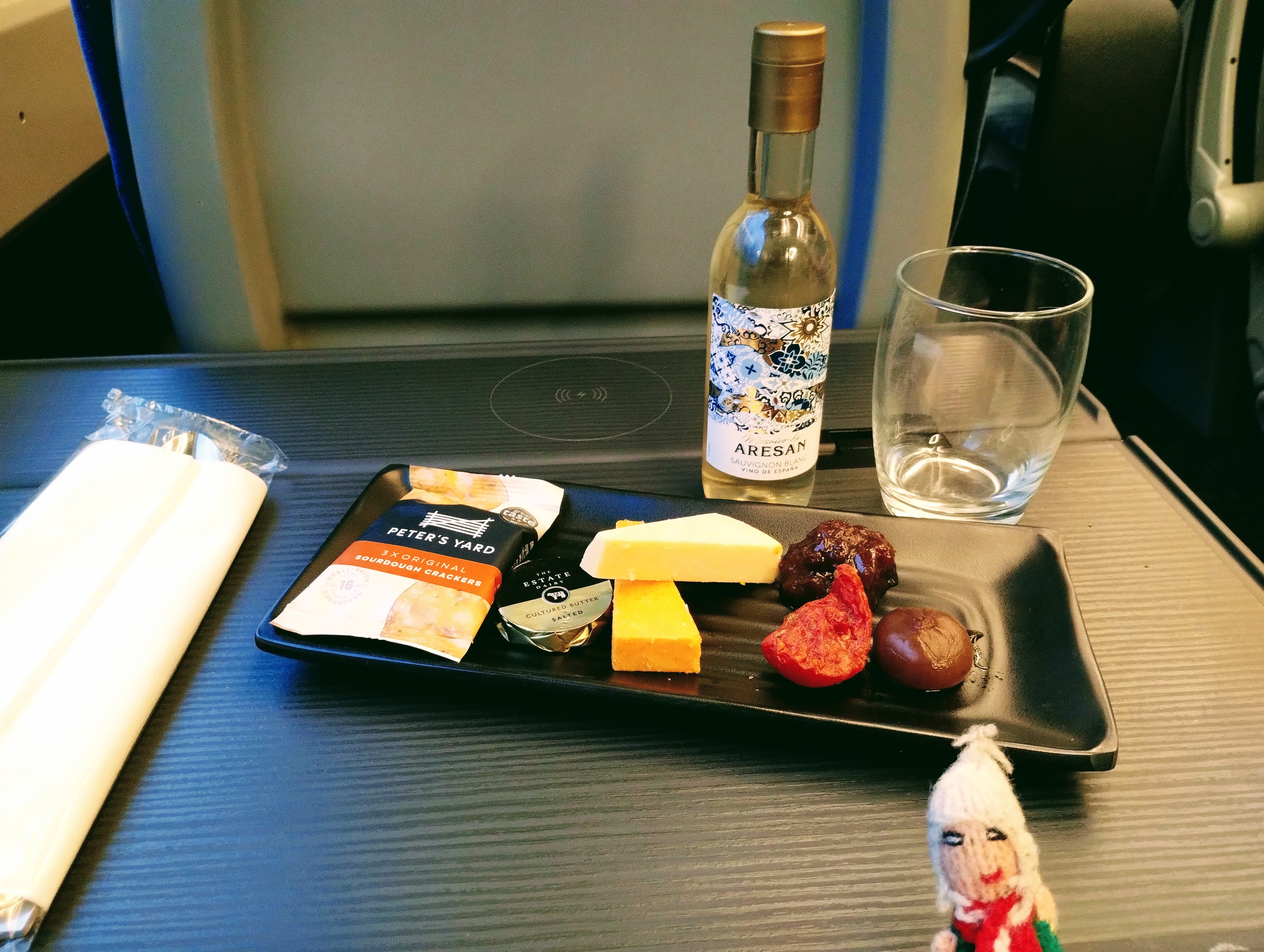A small plate of cheese and biscuits served with antipasti and a glass of white wine.