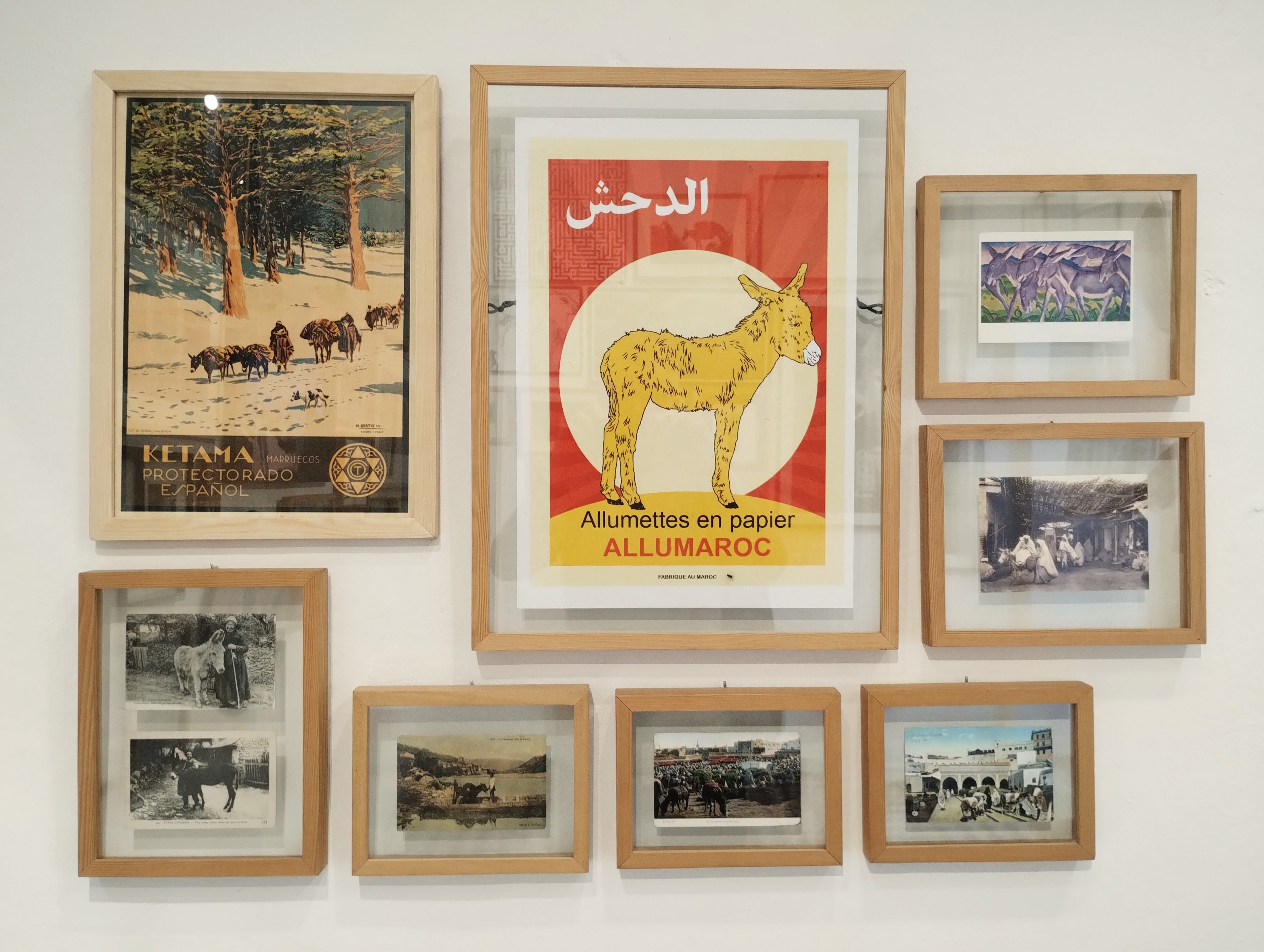 Gallery wall featuring a collection of framed vintage prints and posters with a Moroccan theme, including images of donkeys and advertising posters for paper matches.