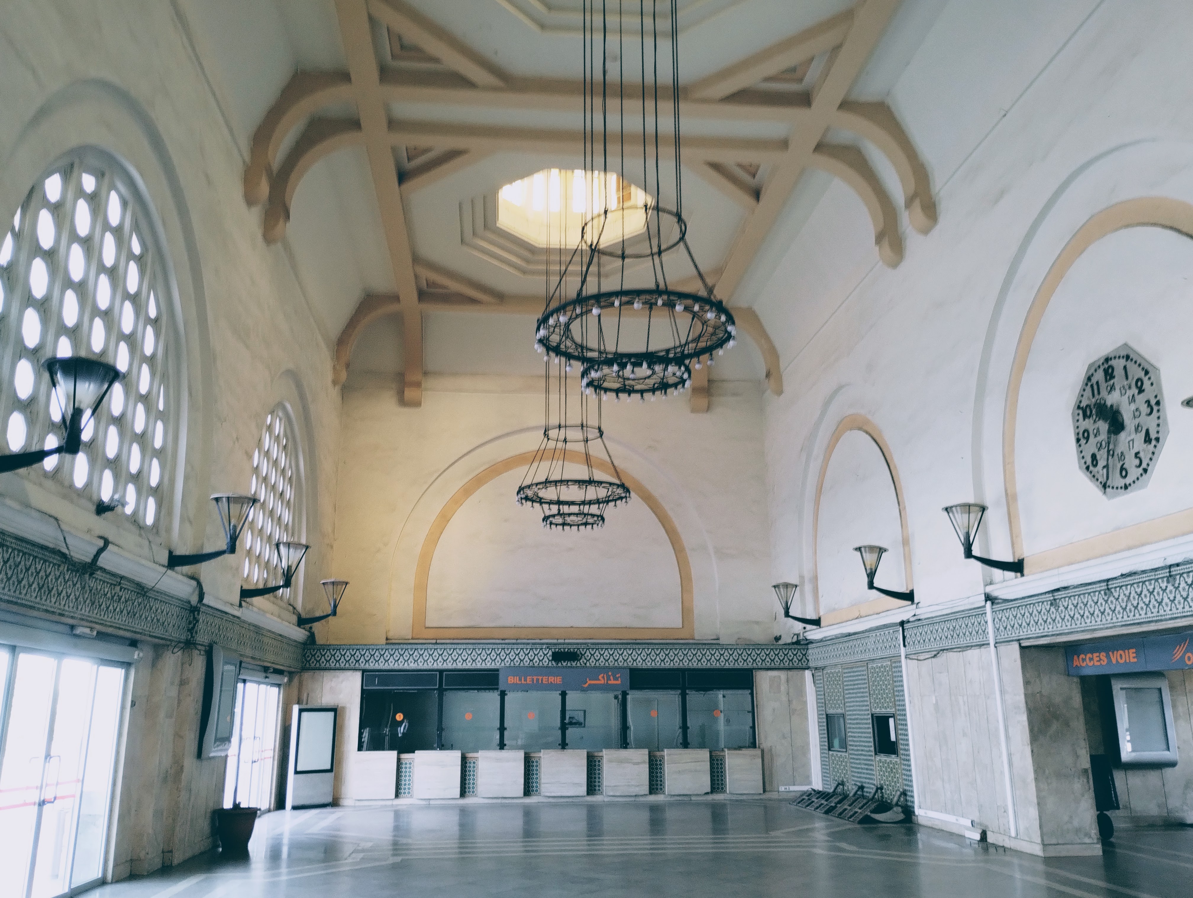 The white and cream interior of the ticket office in the disused Casablanca railway station, with chandeliers and marble floor.