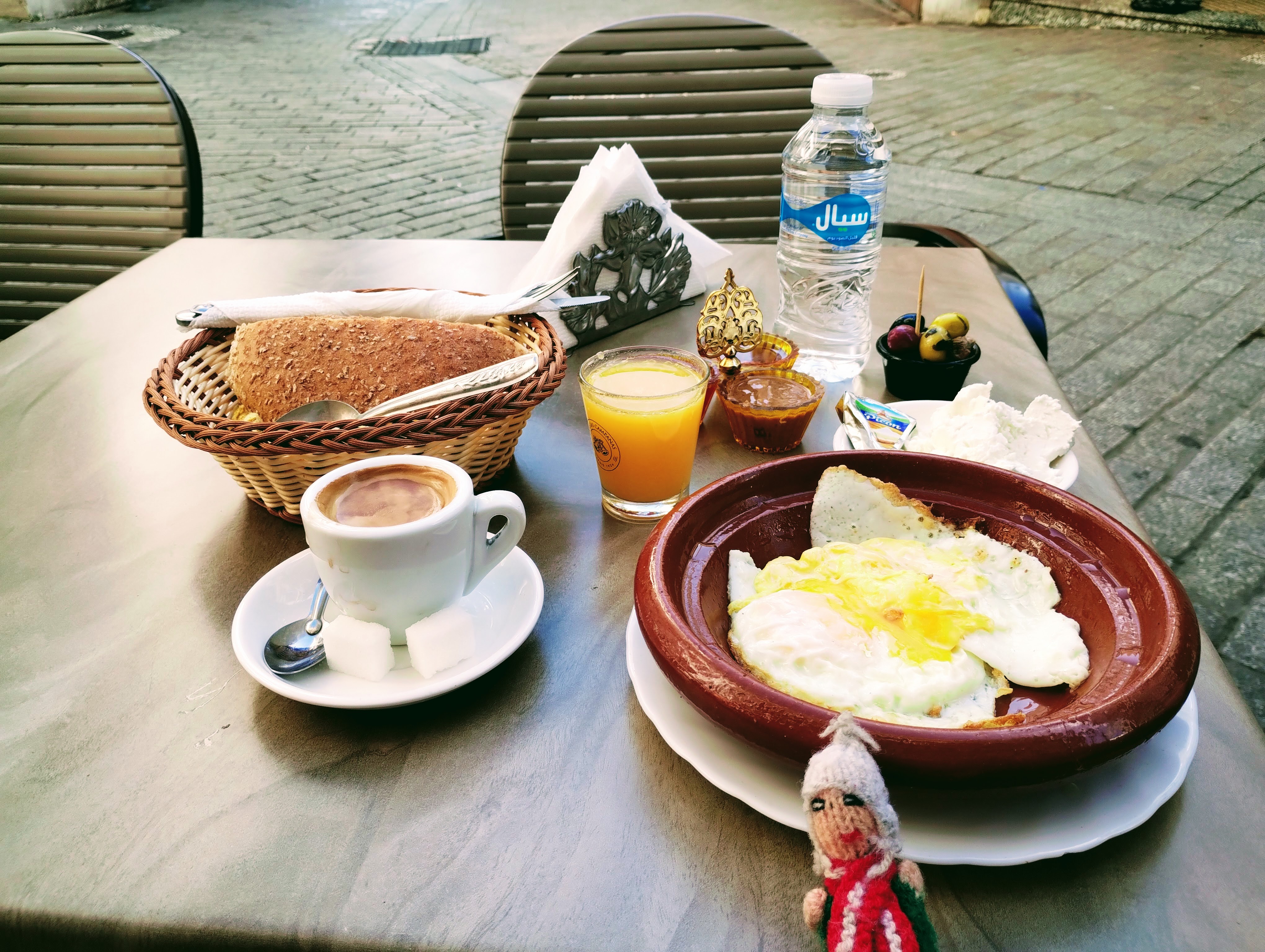 A breakfast of orange juice, coffee, bread, and eggs.